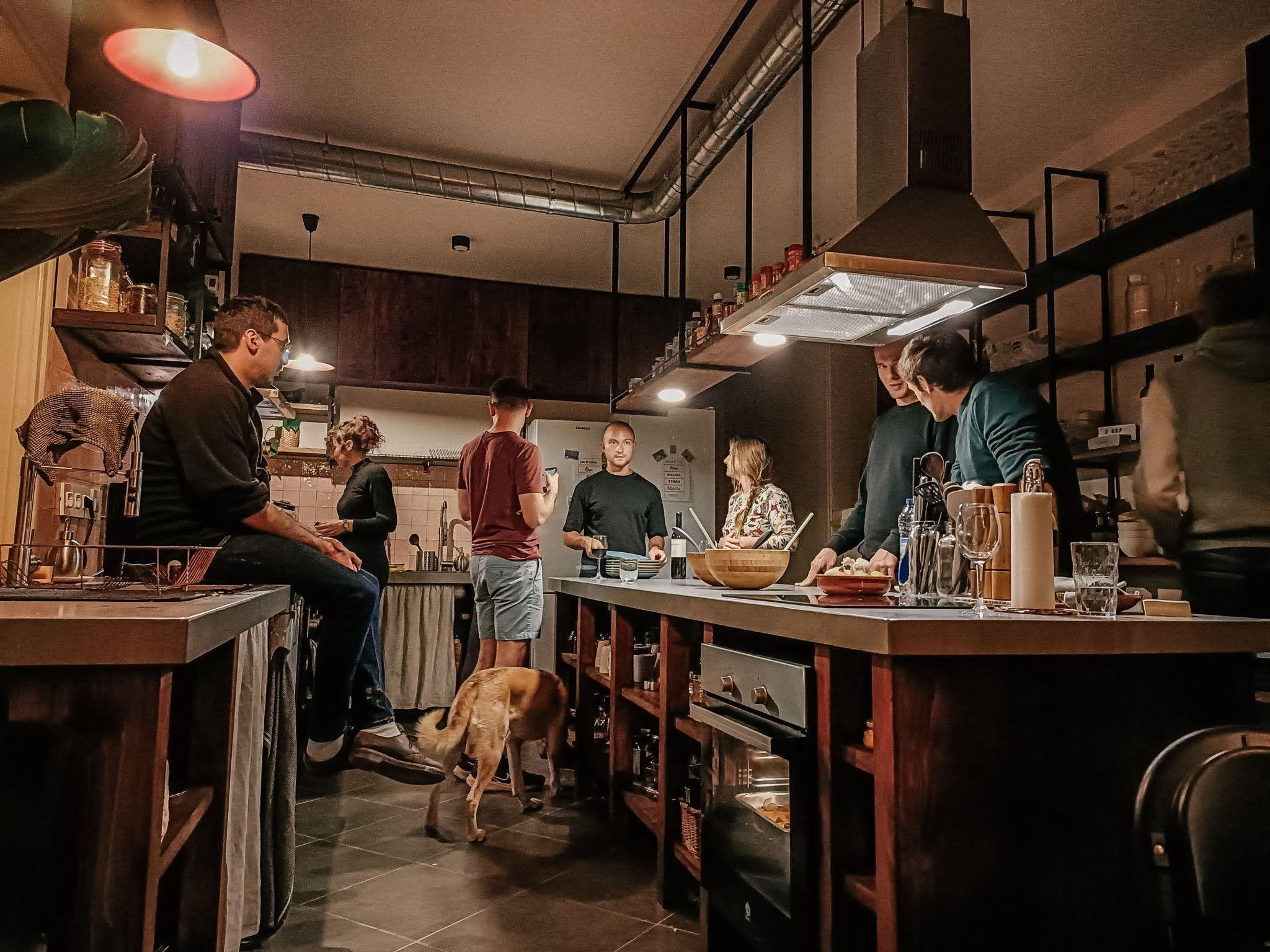 Residents gathered in the shared kitchen for a community dinner, with a dog wandering around.