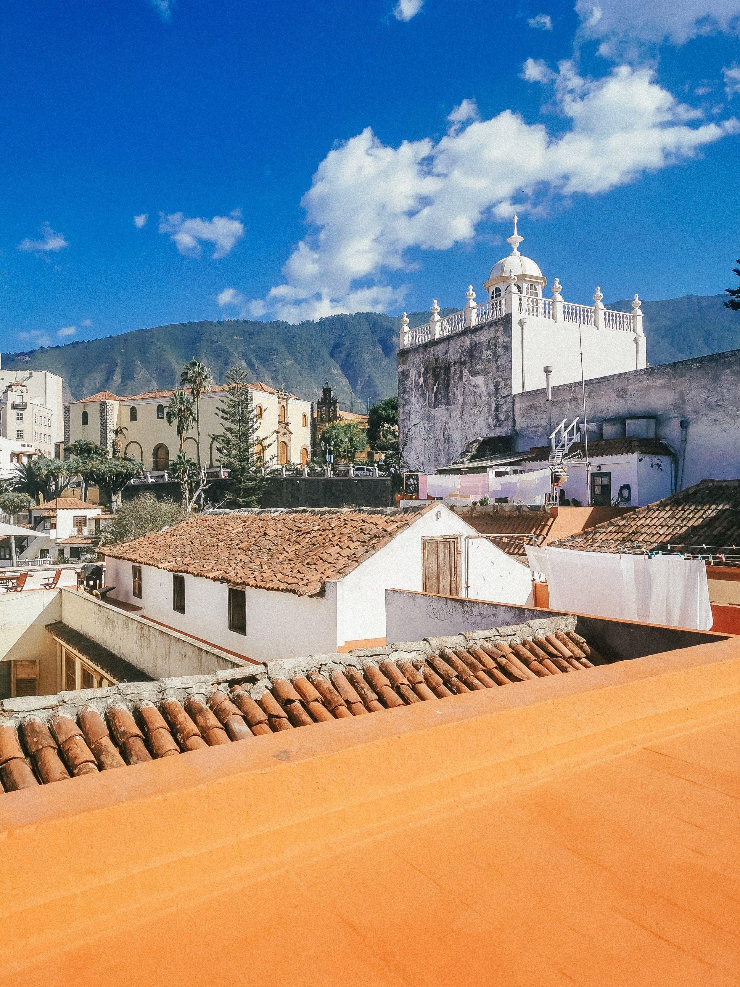 View from the rooftop of Nine Coliving over the terracotta rooftops of La Orotava with a church and mountains in the background.