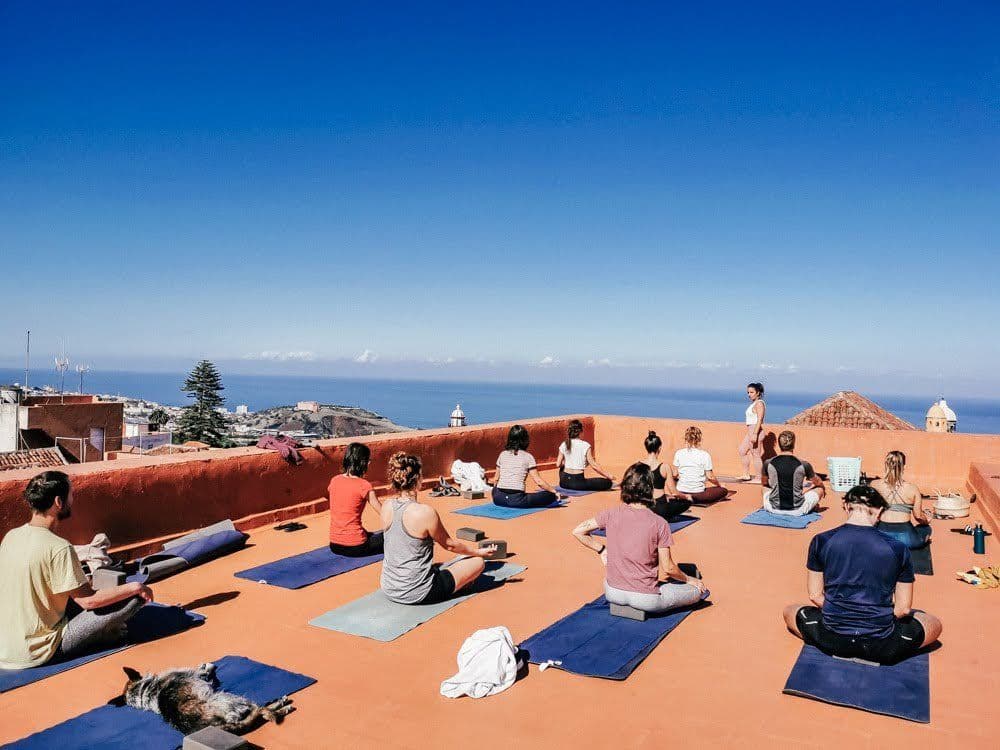 Group yoga session on the rooftop of Nine Coliving with a panoramic view of the sea and blue sky.