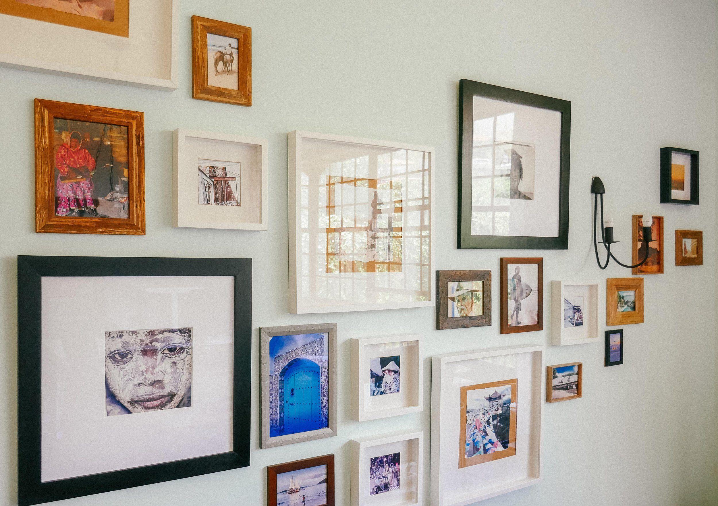 A gallery wall with framed travel photographs and artwork in the living room of Nine Coliving.