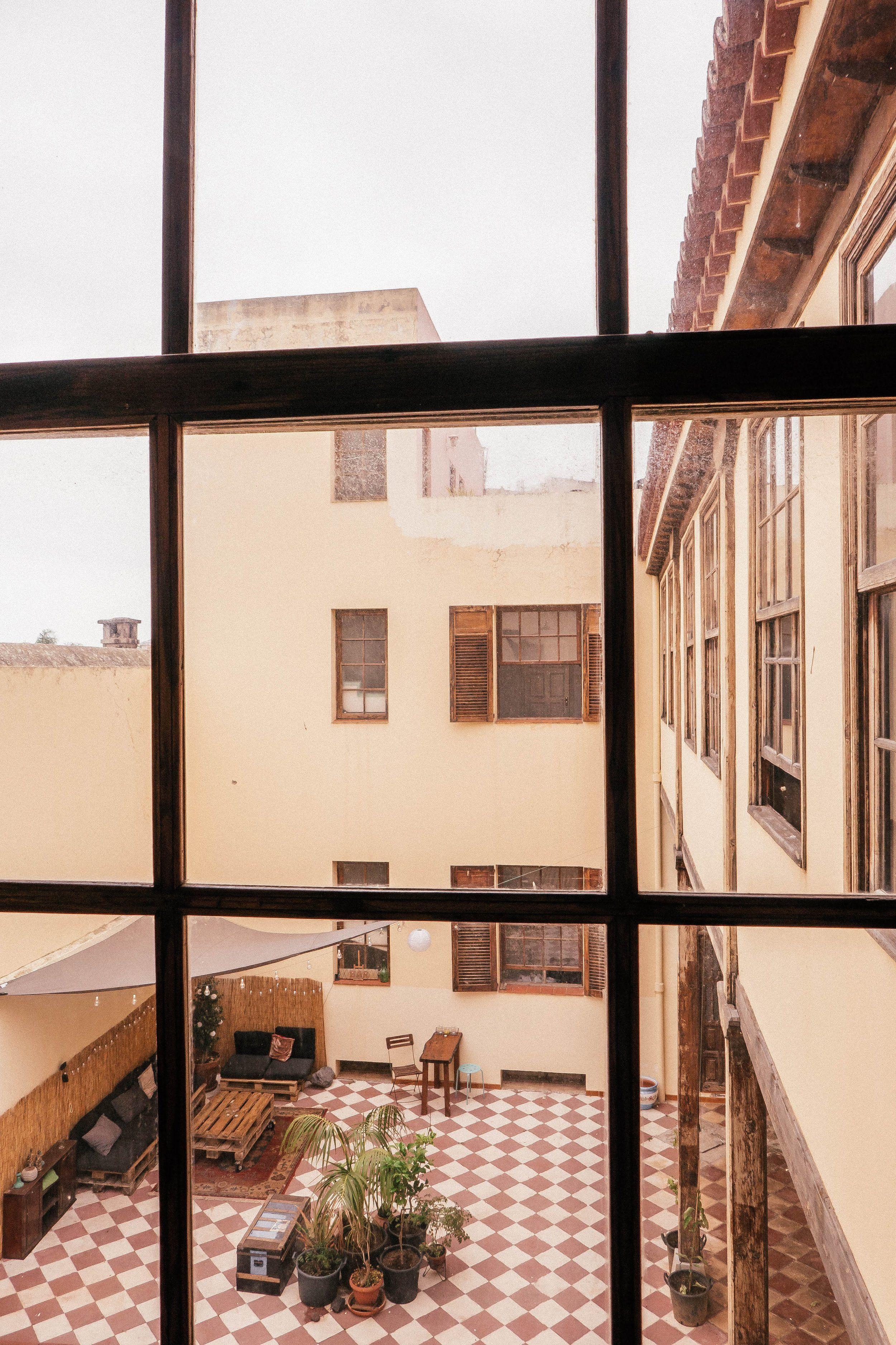 View of the internal patio through a window at Nine Coliving.
