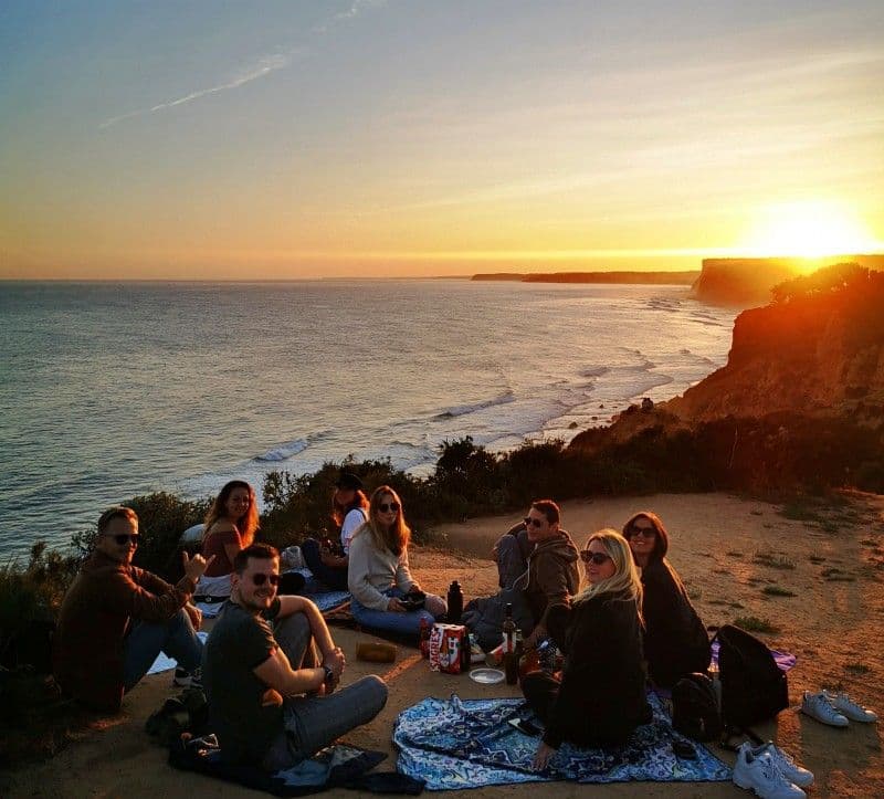 International community of digital nomads and remote workers at Noma Village coliving Lagos — group gathered at sunset on the cliffs