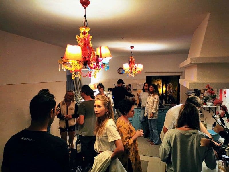 Community members socializing in the kitchen area with colorful chandeliers