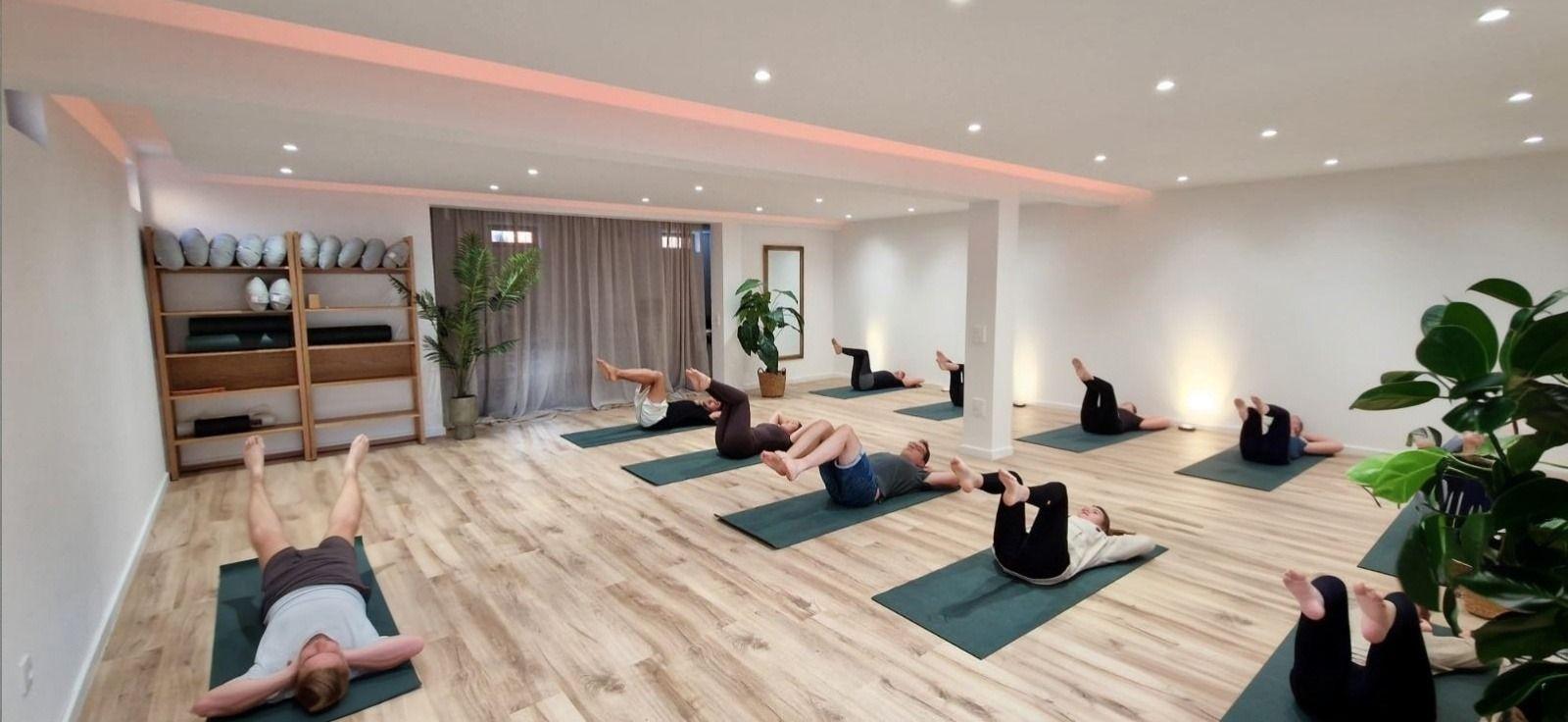 Workout and yoga shala — group yoga/pilates session in a dedicated indoor studio with wooden floors
