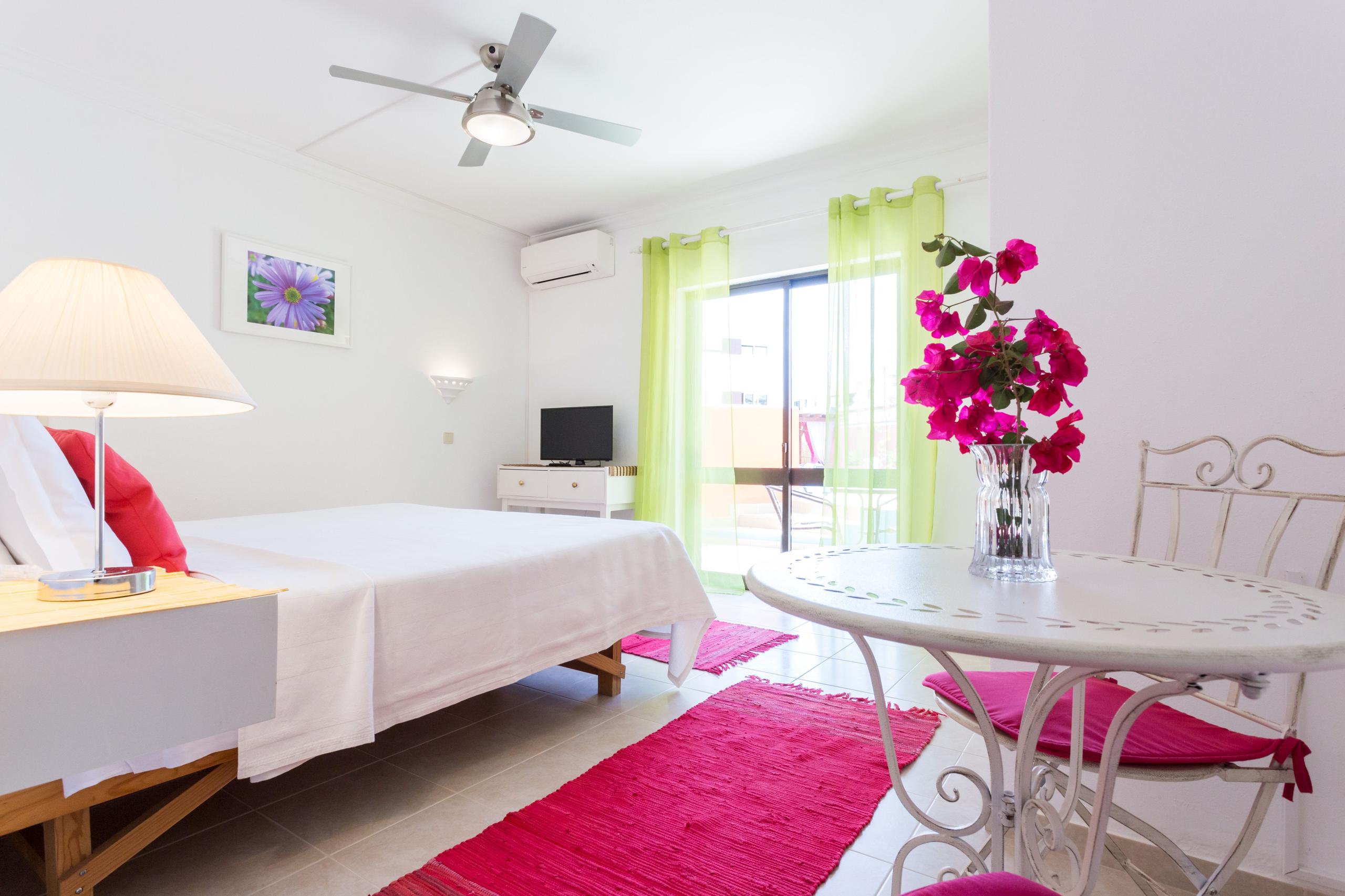 Private coliving room with queen bed, work desk, TV and balcony access to pool area