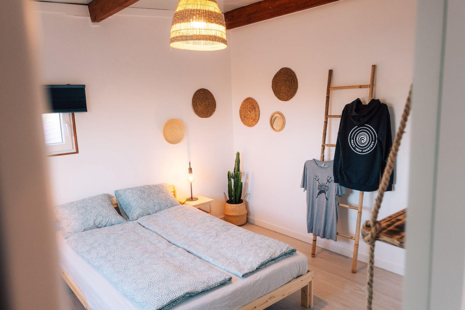 Cozy bungalow bedroom with surfboard-themed decor and wicker lamp at the Sea View Hub