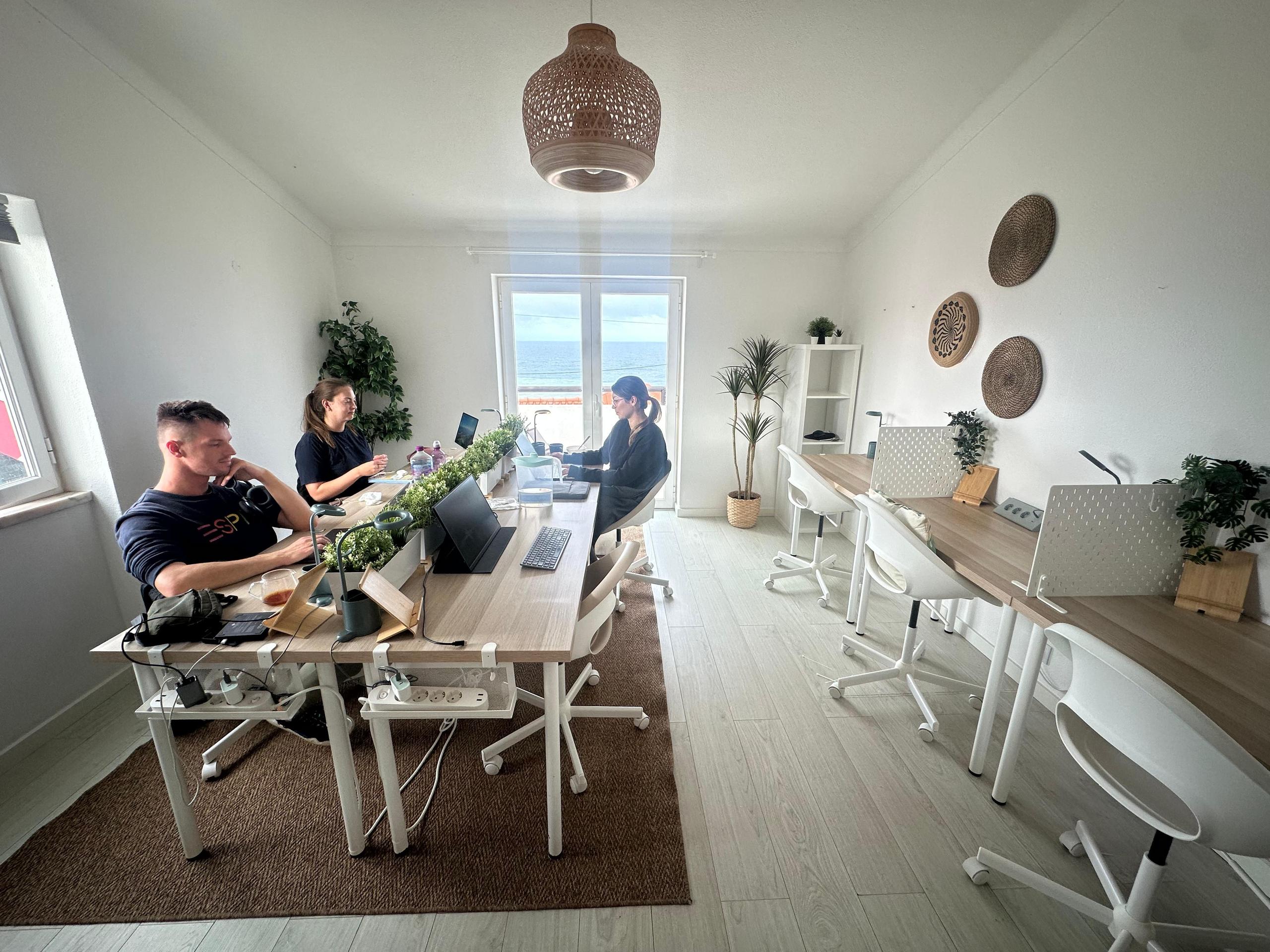 Bright dedicated coworking space at the Sea View Hub with people working at desks and sea view through the window