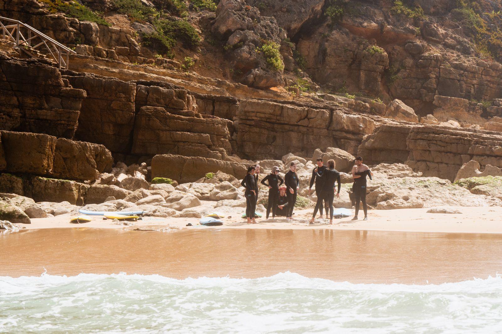 Group of people in wetsuits with surfboards at a rocky beach near Ericeira
