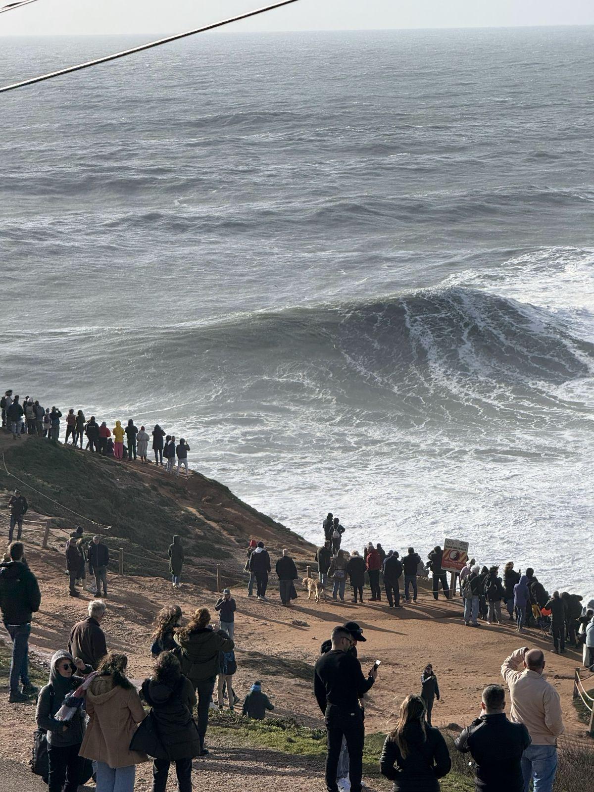 Crowd watching massive waves at Nazaré, a popular day trip destination from Ericeira