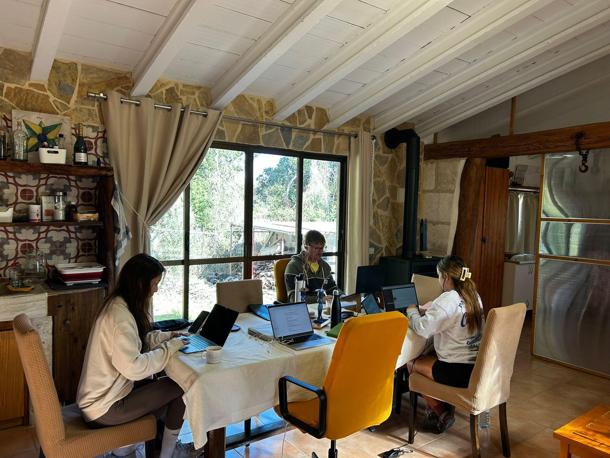 Guests working on laptops at large tables inside the coworking house