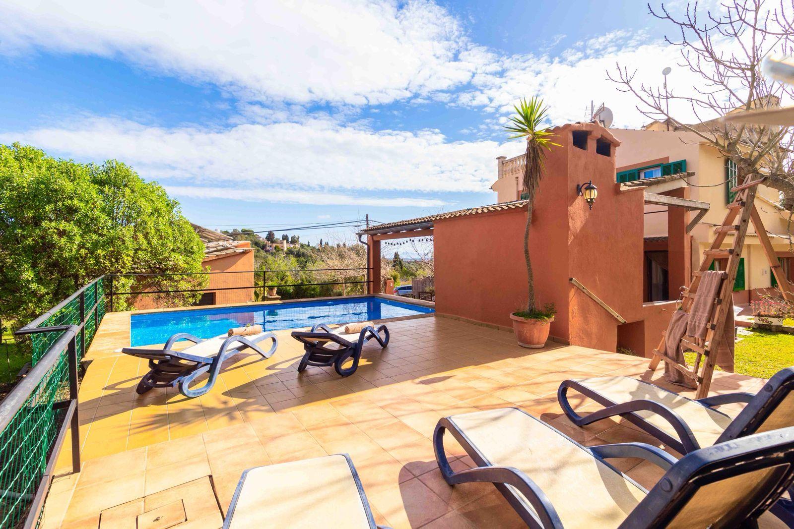 Outdoor pool area with sun loungers and the coliving building in the background