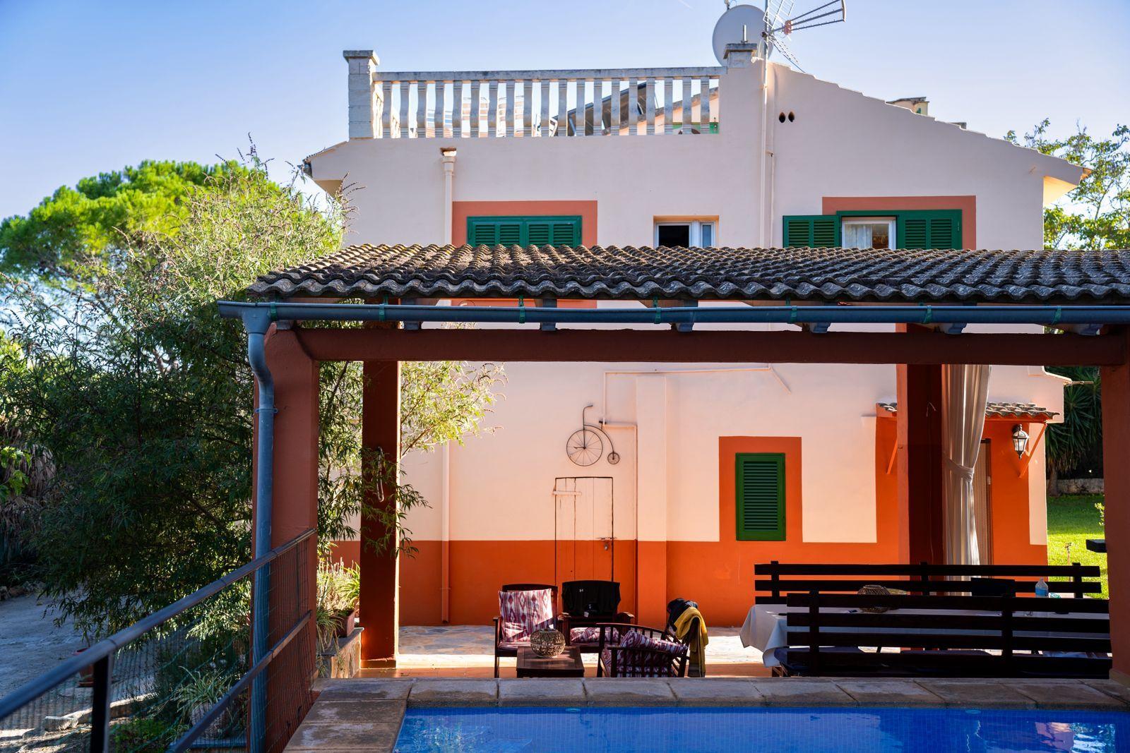 Exterior view of the coliving home showing the pool in the foreground and covered patio area