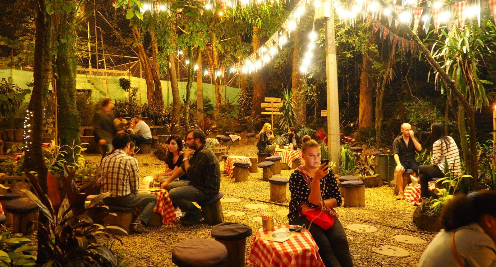 Outdoor bar or restaurant in Medellin with string lights, lush trees, and people socializing at night