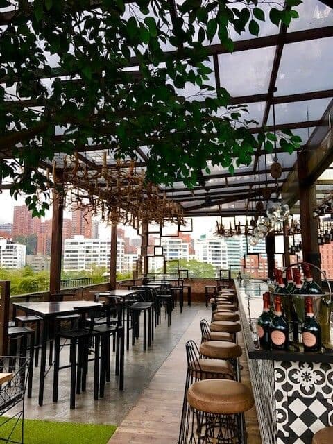Rooftop bar or restaurant in Medellin with city views, lush plants, and bar seating