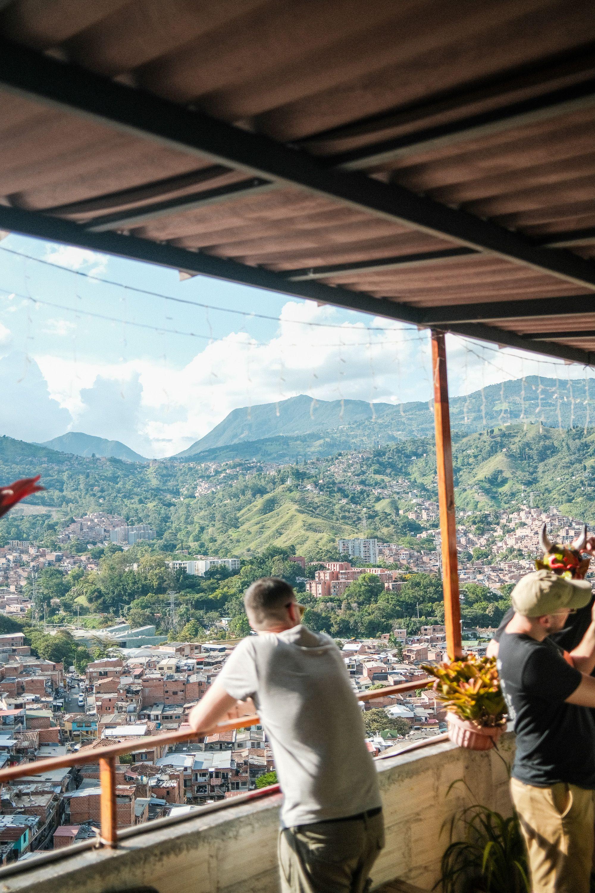 Two people looking out over Medellin city and mountains from a covered terrace