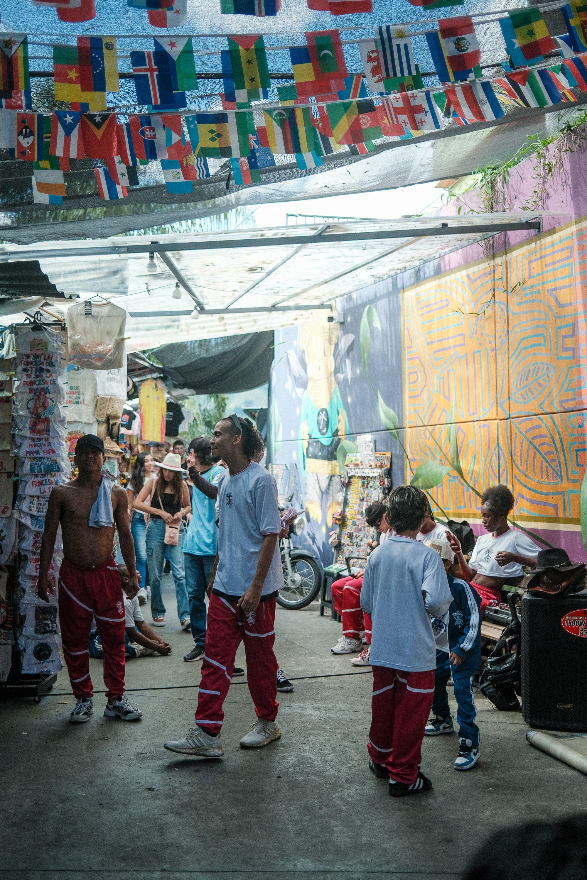 Street scene in Medellin's Comuna 13 with colorful murals and people dancing