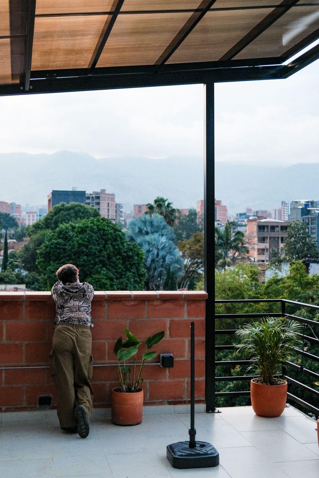 Person standing on the rooftop terrace overlooking the Medellin cityscape and mountains
