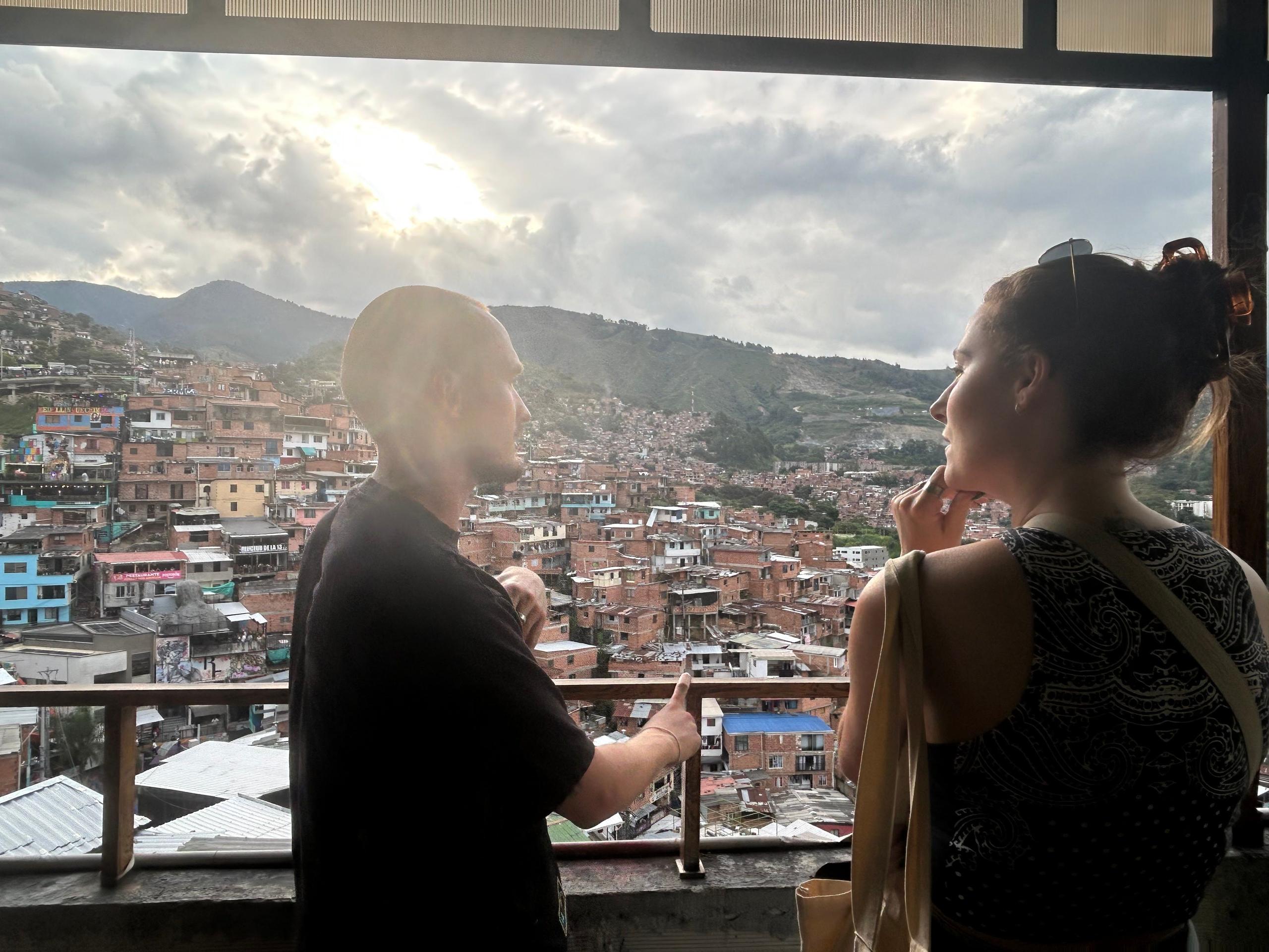 Two people looking out over the Medellin hillside neighborhoods from a viewpoint in Comuna 13