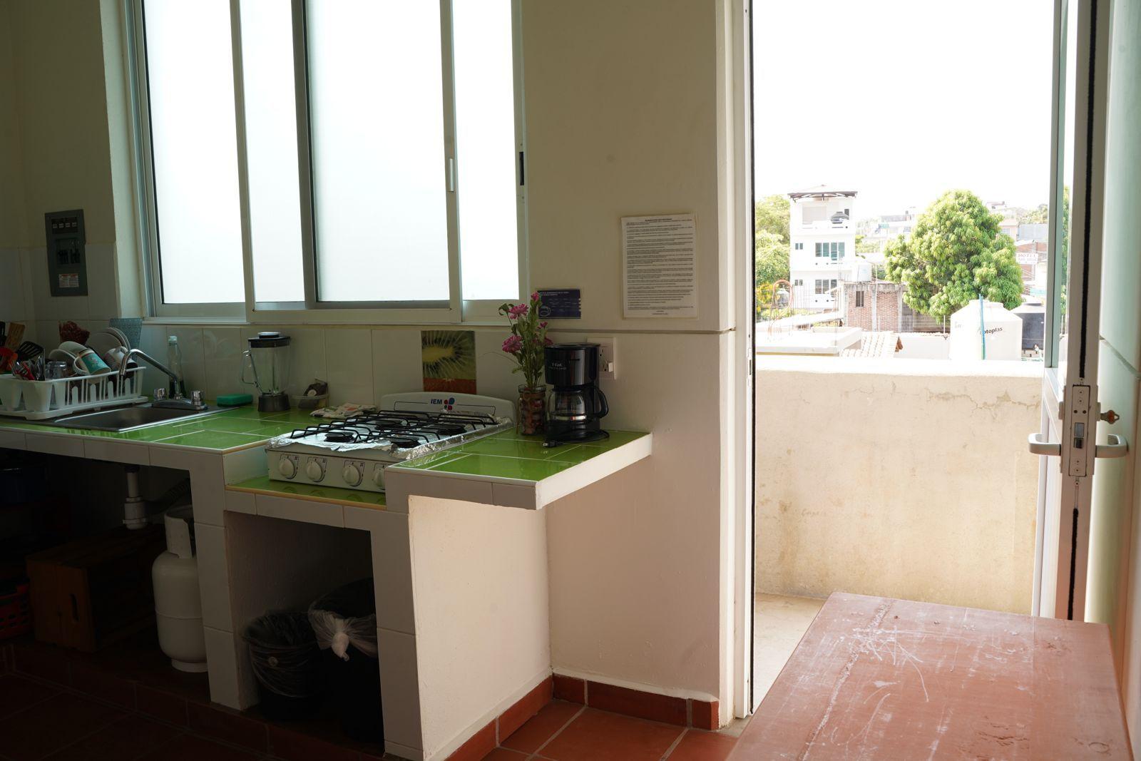 Fully equipped shared kitchen with gas stove, coffee maker, and view to the outside