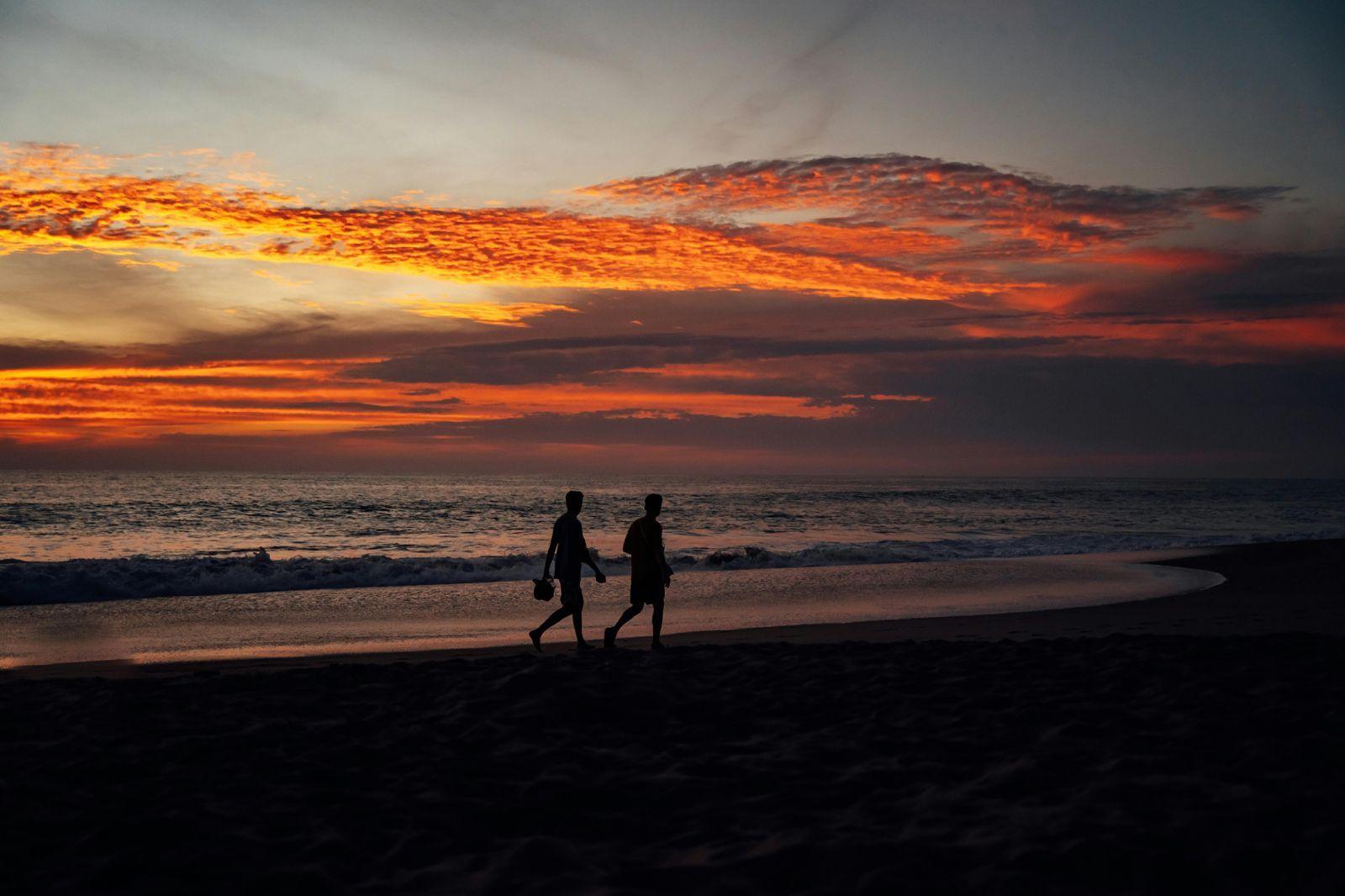 Two people walking on the beach at sunset in Puerto Escondido