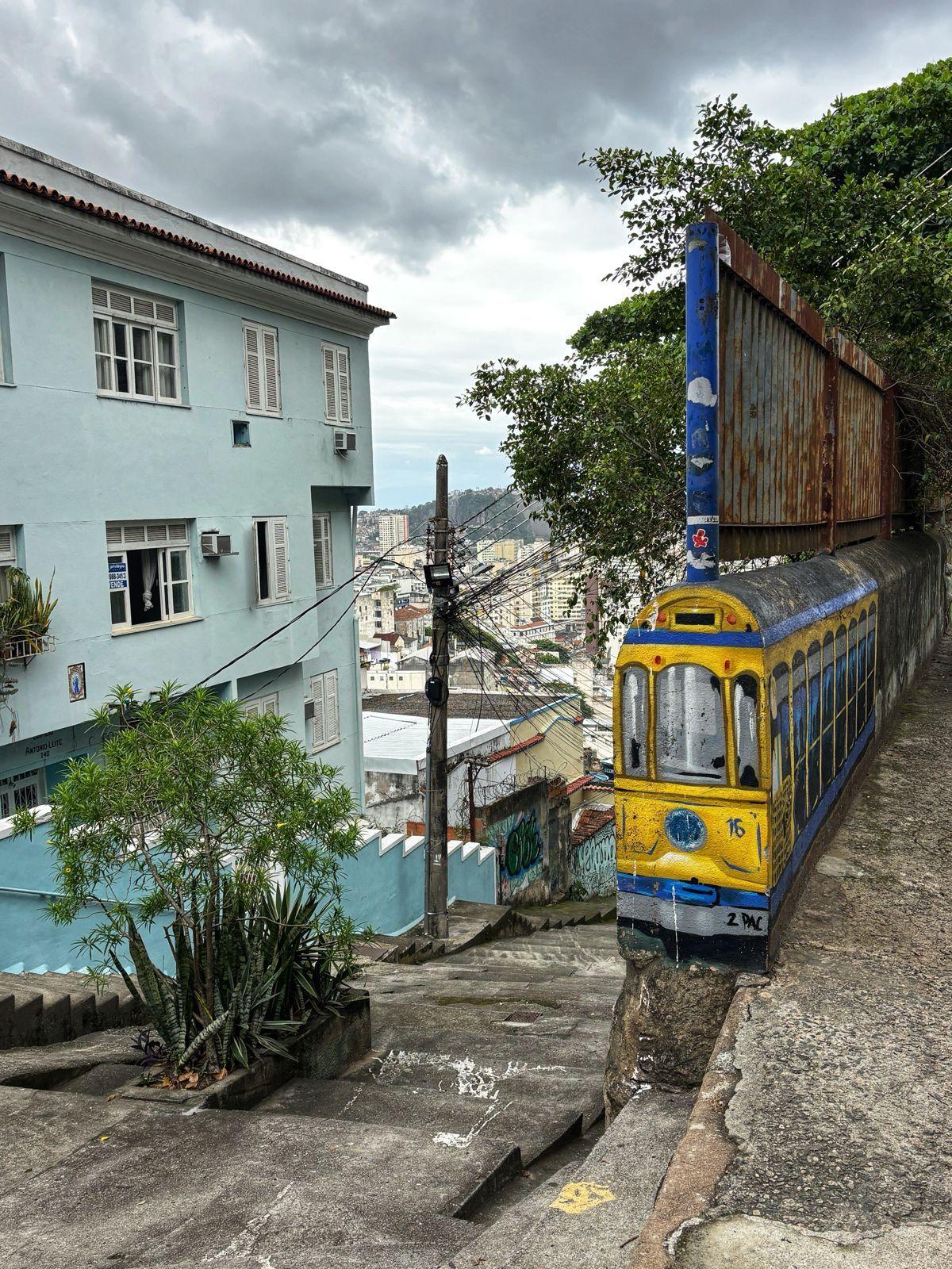 Colorful street art depicting a yellow tram on a cobblestone street in Santa Teresa, Rio de Janeiro