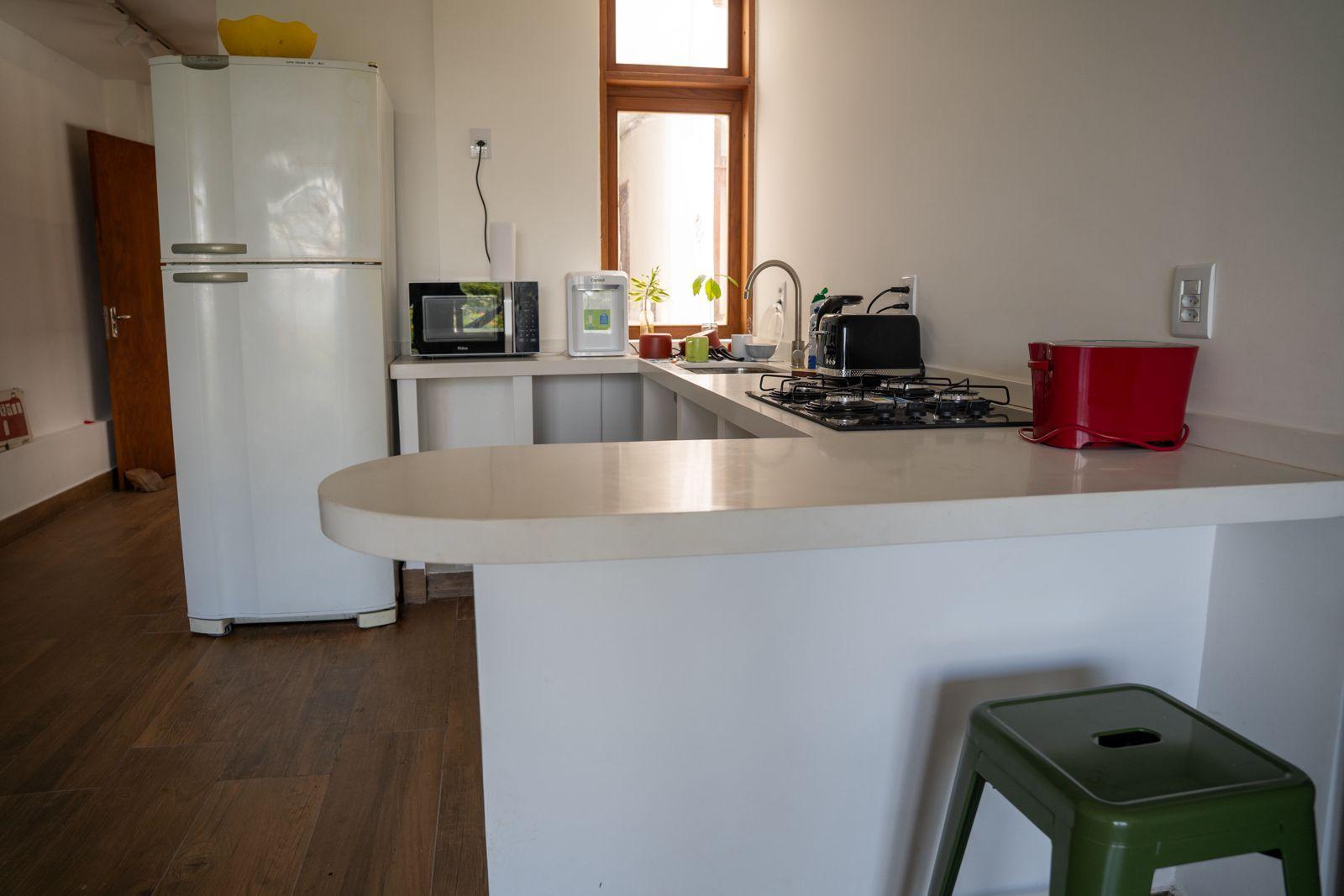 Fully equipped shared kitchen with refrigerator, microwave, gas stove, coffee maker, and kitchen counter with bar stool