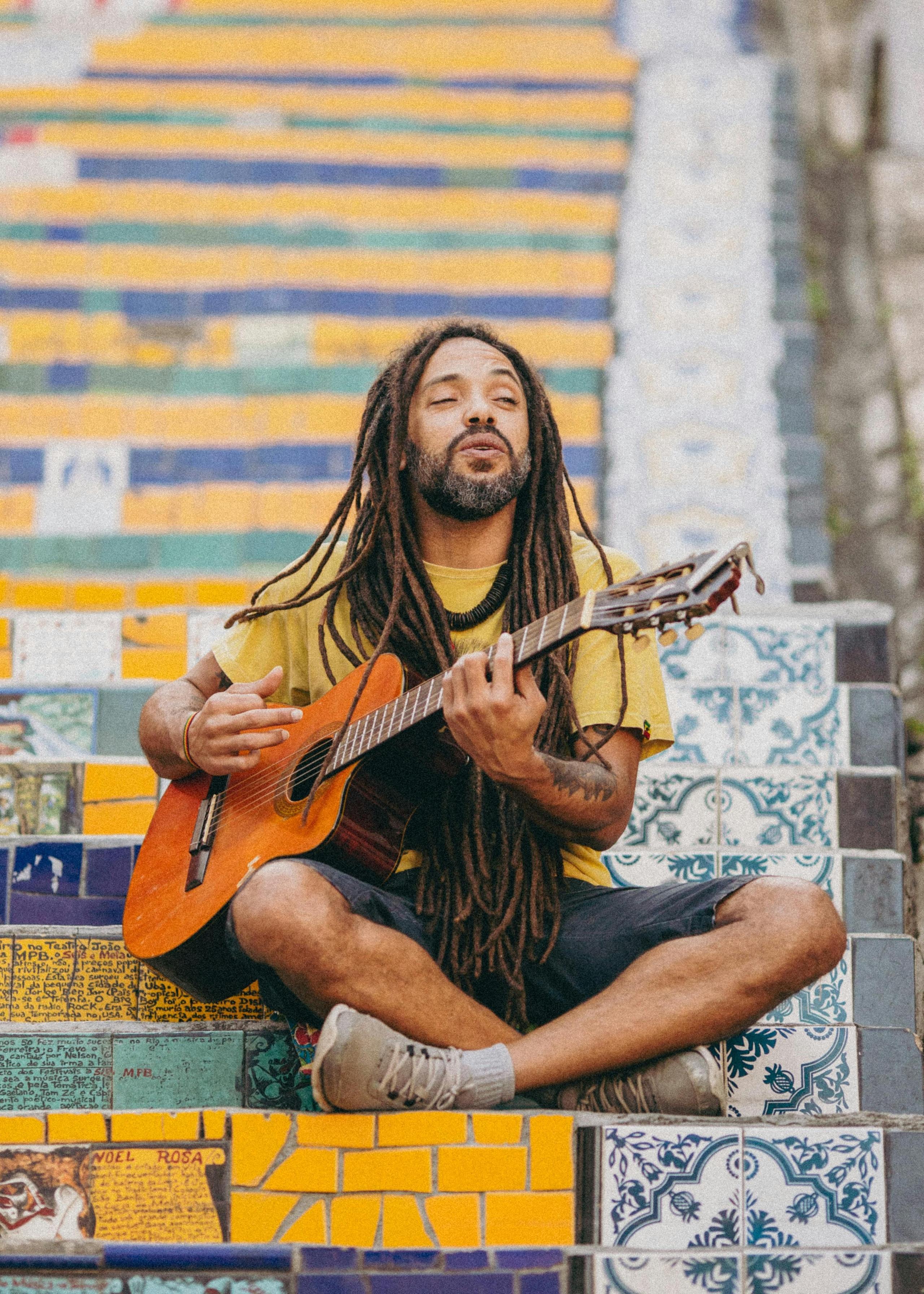 A musician with dreadlocks playing guitar on the colorful tiled Escadaria Selarón steps in Rio de Janeiro