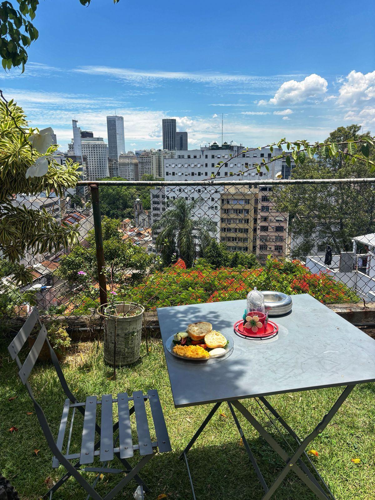 A table with breakfast food set up in the garden terrace overlooking the Rio de Janeiro city skyline