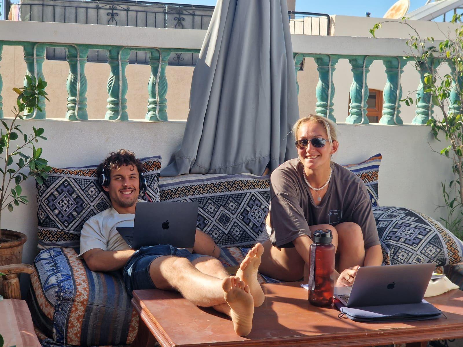 Two nomads relaxing and working on laptops on the rooftop terrace at Abdel Yan