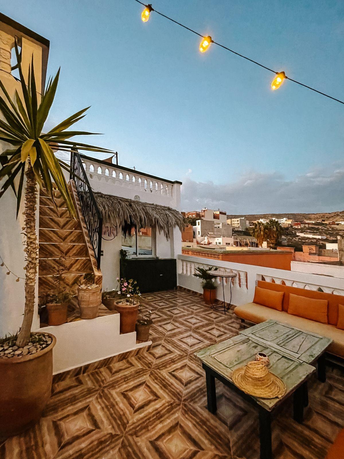 Cozy rooftop terrace at Louise's Home with string lights, plants, and a seating area with views of the village