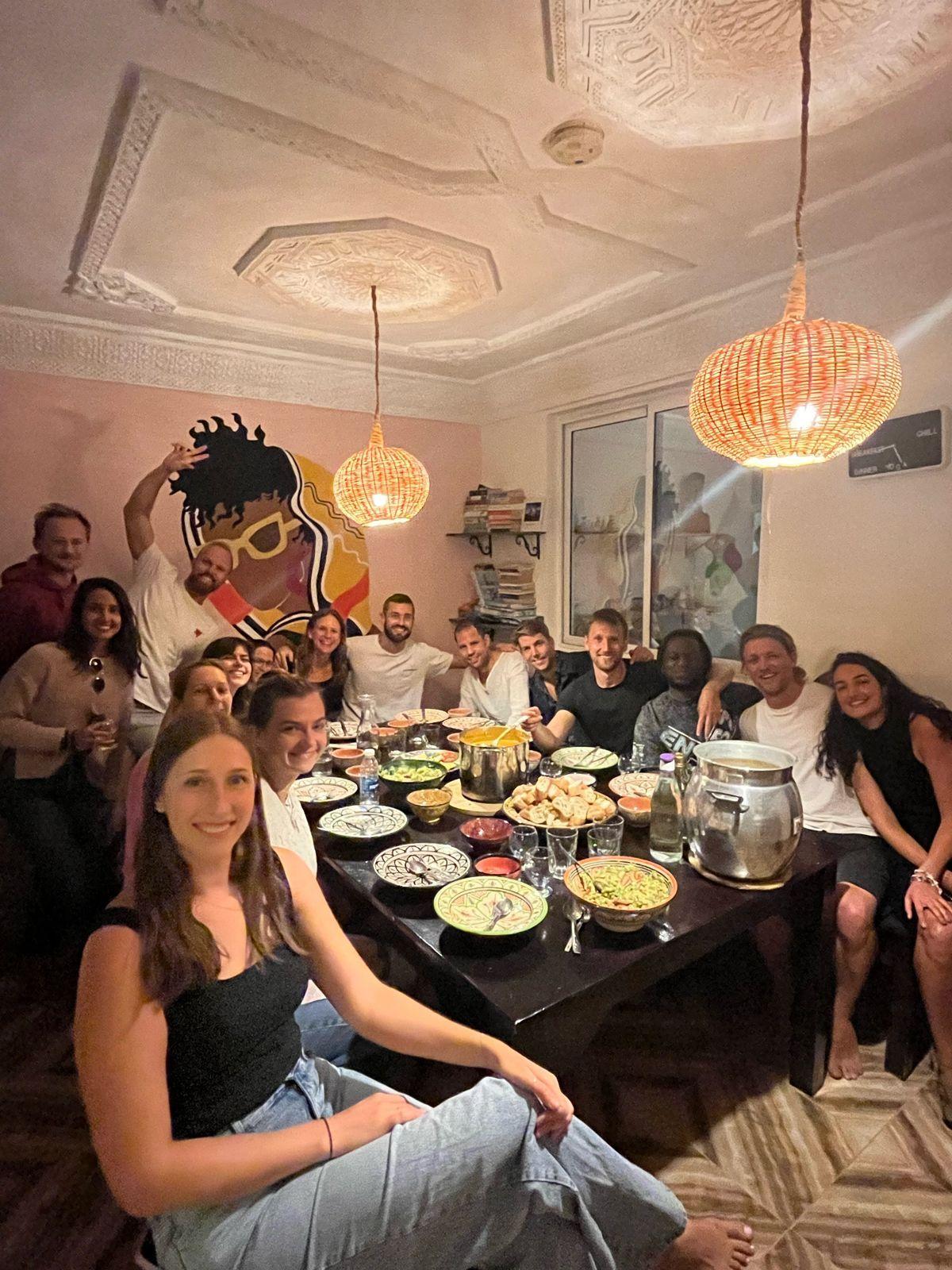 Large group of nomads sharing a community dinner around a table at Louise's Home