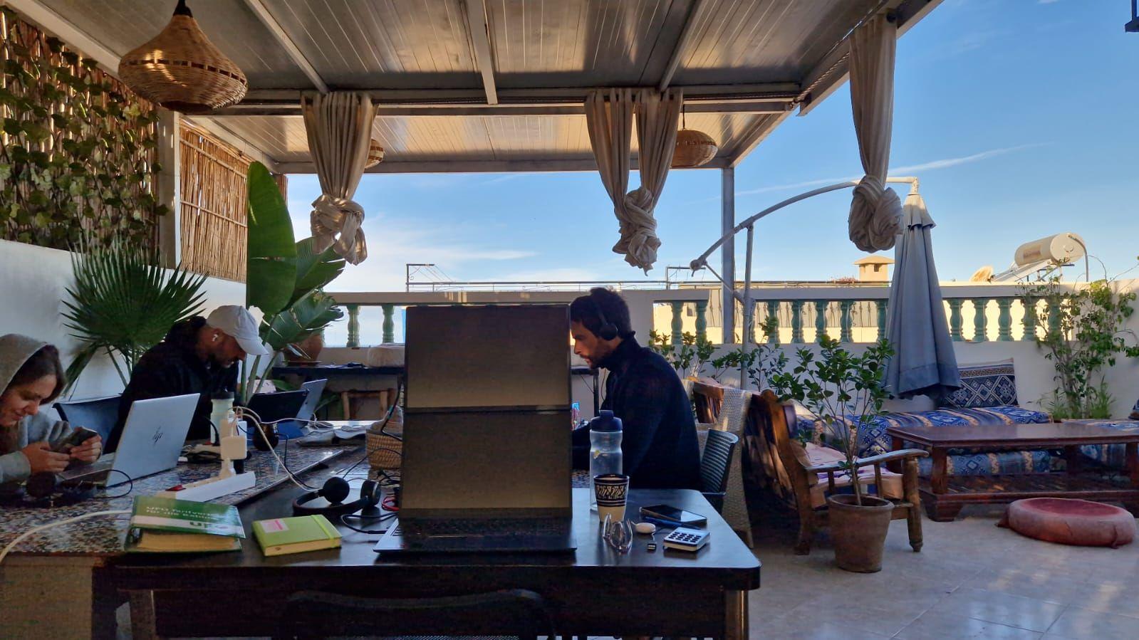 People working on laptops on the semi-covered rooftop coworking space at Abdel Yan