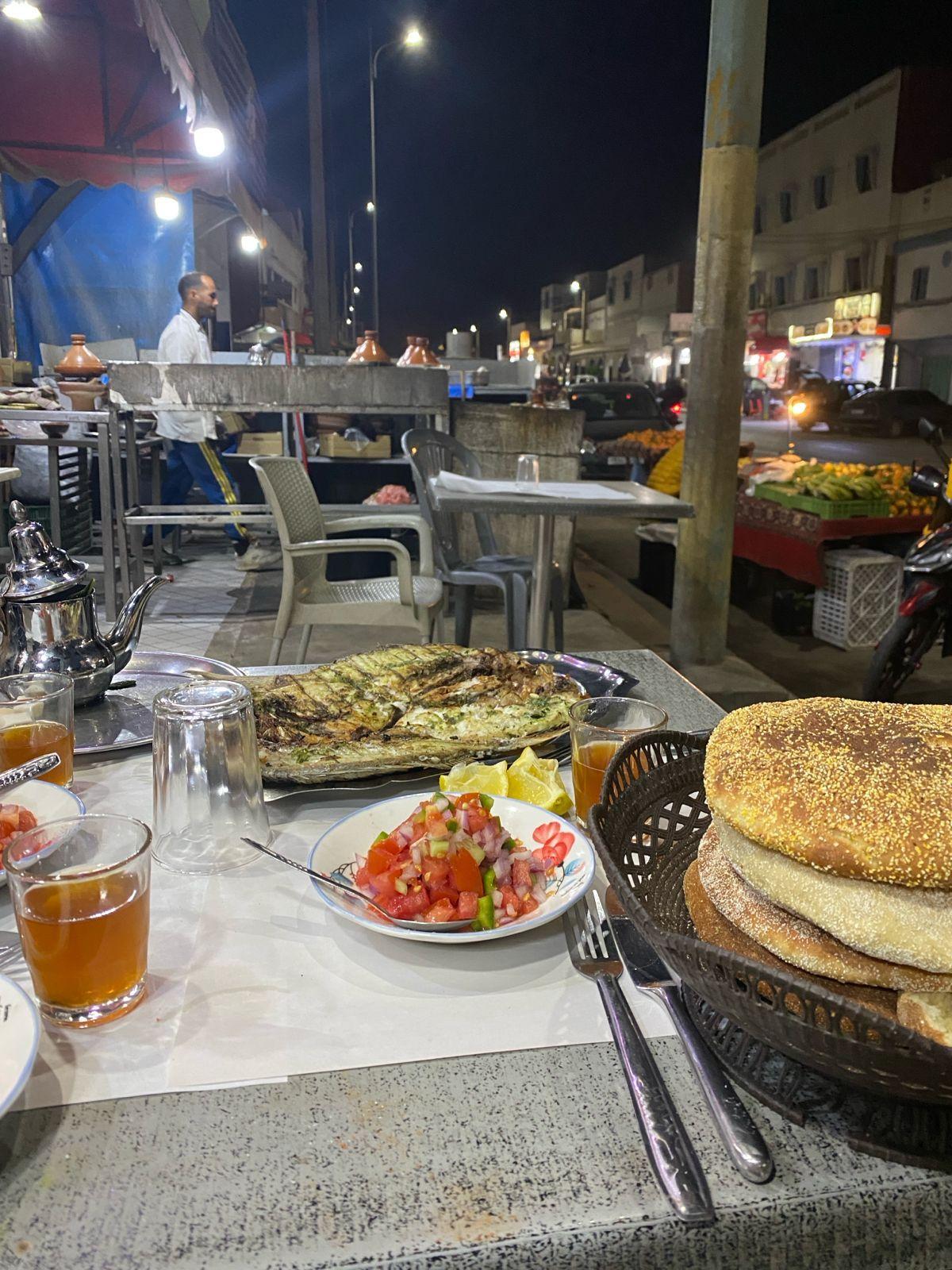 Fresh grilled fish with Moroccan salad and bread at a local outdoor restaurant in Aurir