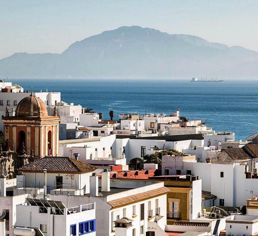 View over Tarifa's white-washed old town rooftops with the Strait of Gibraltar and the coast of Africa visible in the background