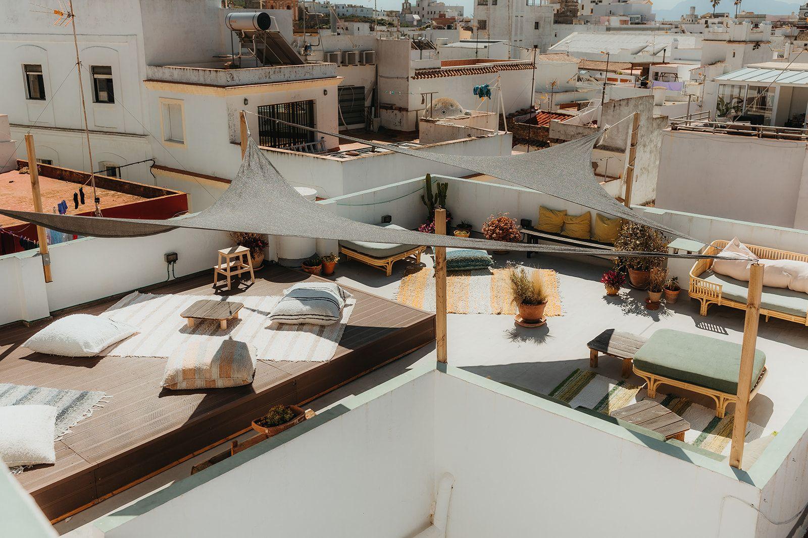 Rooftop terrace at Tarifa Hub with sun shades, loungers, cushions, and views over the town rooftops