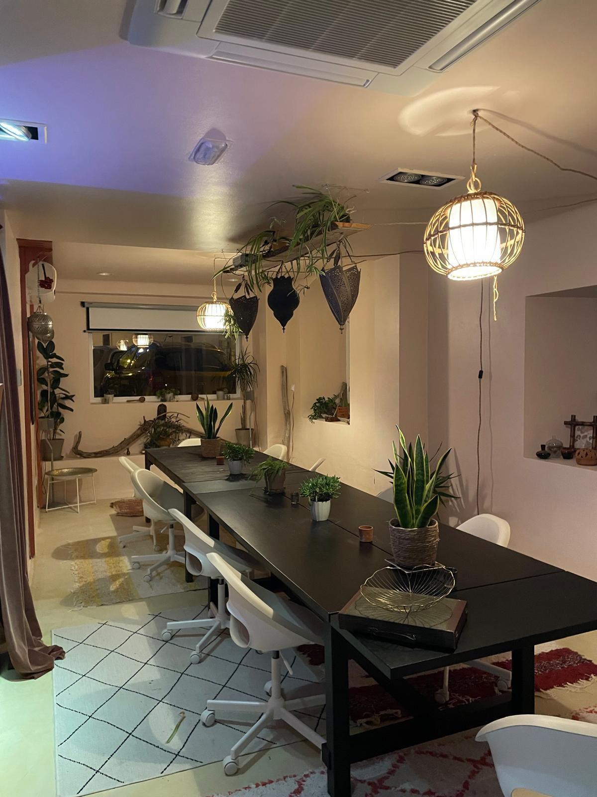 Coworking space at Tarifa Casa in the evening with long desk, chairs, and hanging plants