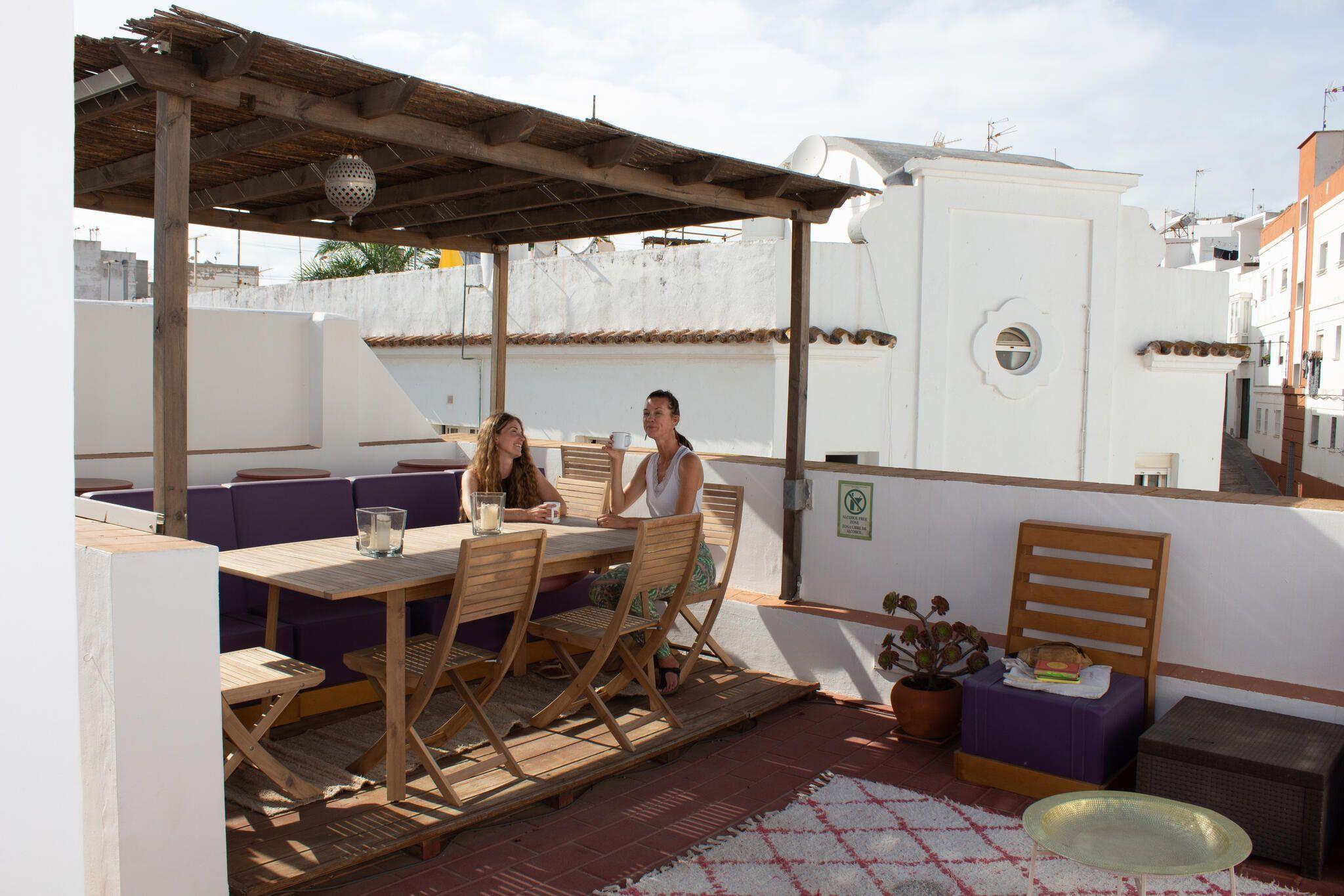 Rooftop terrace at Tarifa Casa with wooden pergola, dining table, chairs, and views of the old town