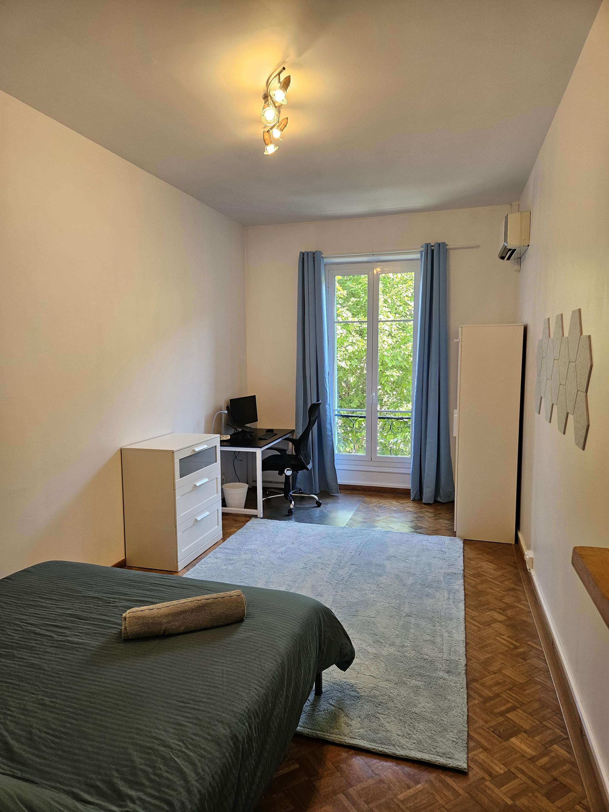 Private room Mont Boron showing bed, desk with monitor, wardrobe and window with blue curtains