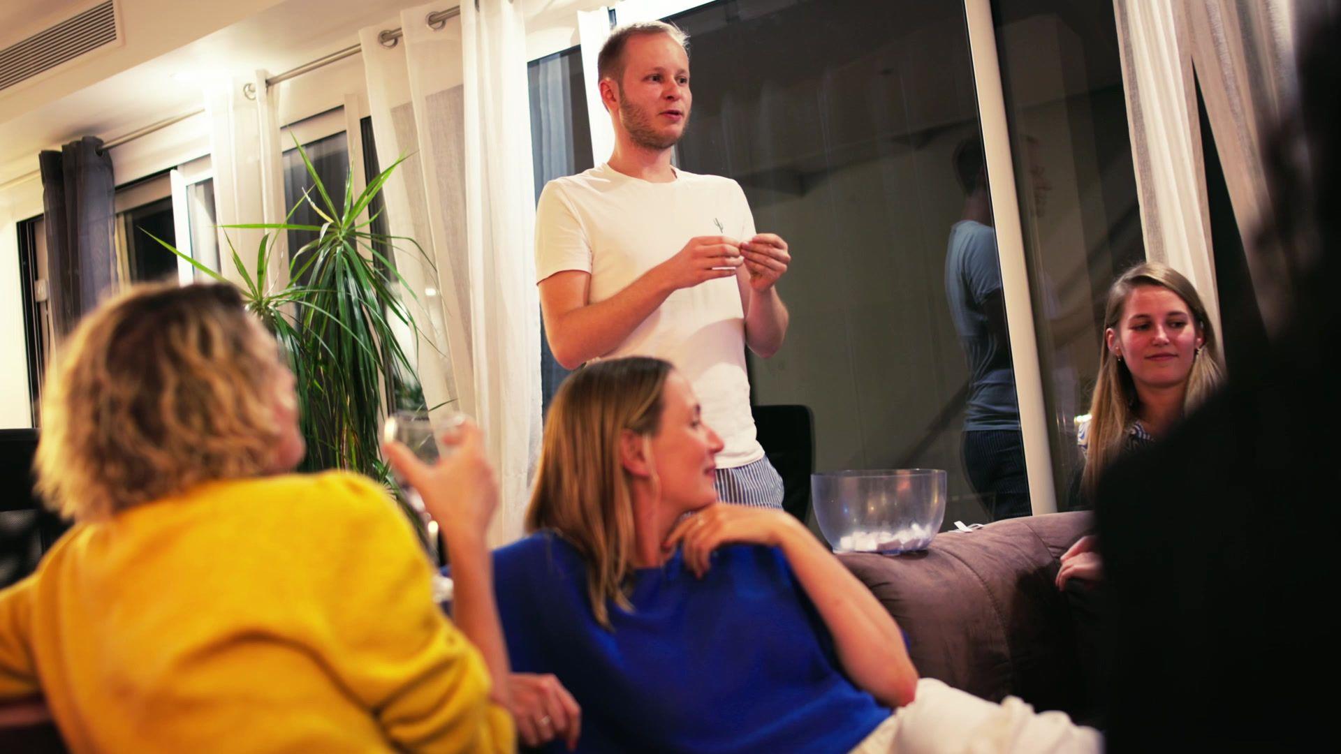 Group of coliving residents socialising in a living room in the evening