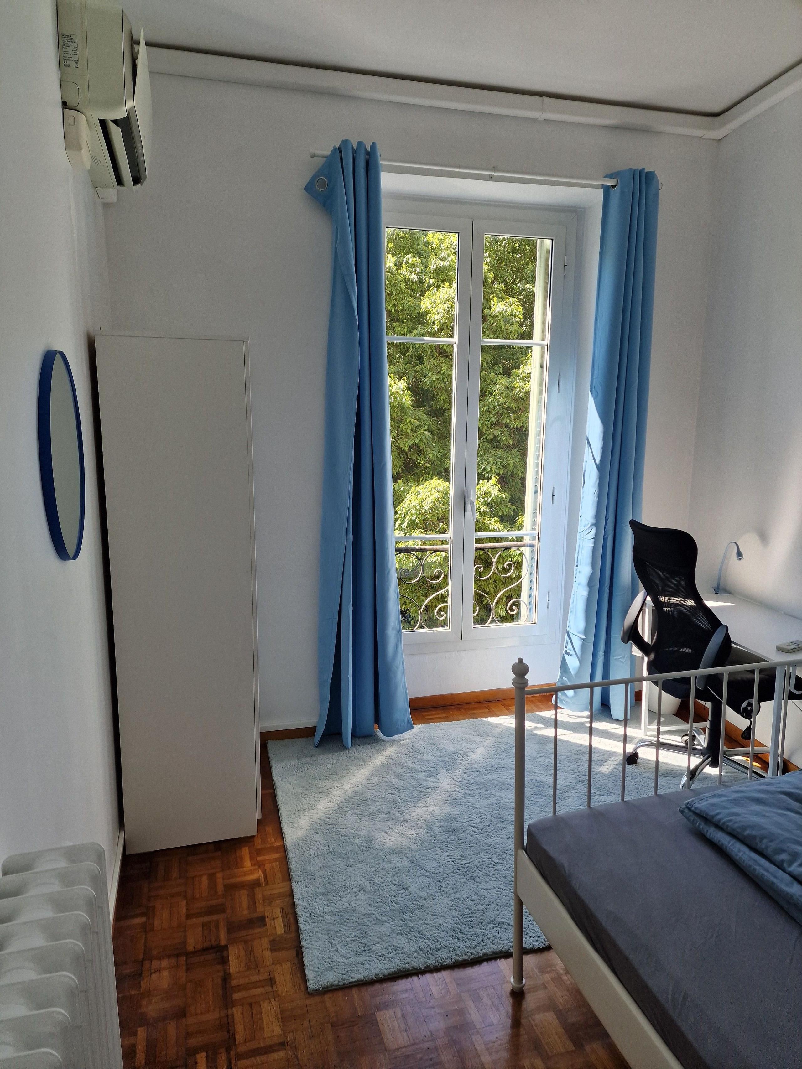Private room Promenade viewed from above, showing bed with blue bedding, window with blue curtains and parquet floor