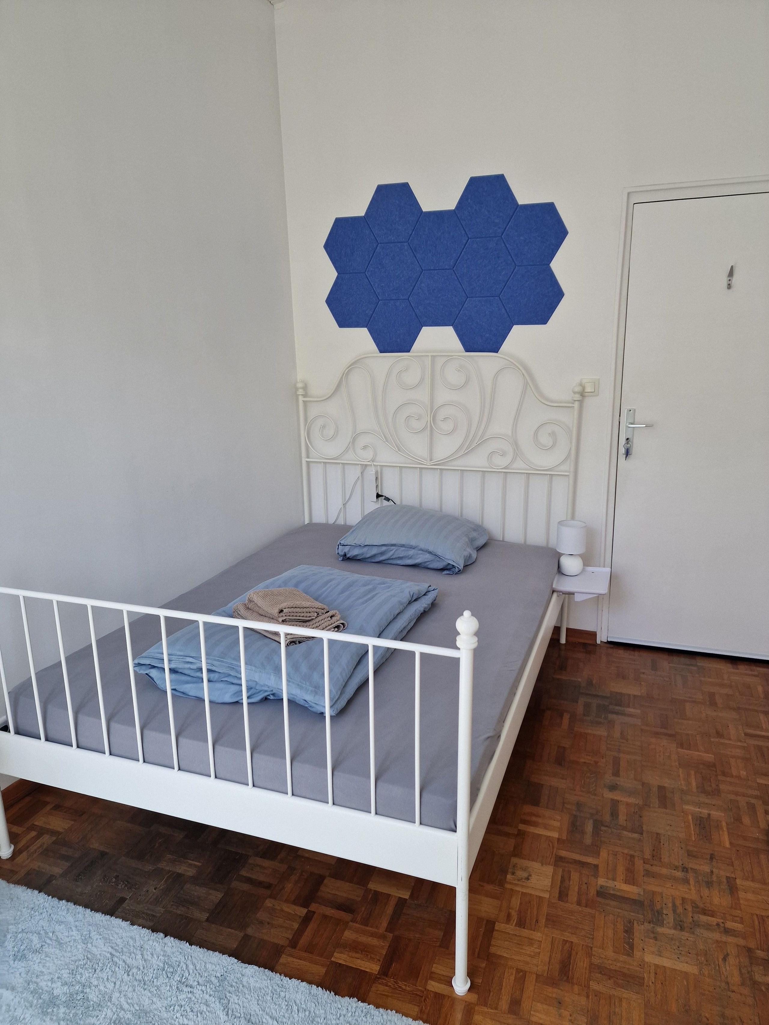 Private room Promenade showing ornate white metal bed frame with blue hexagonal acoustic panels on wall