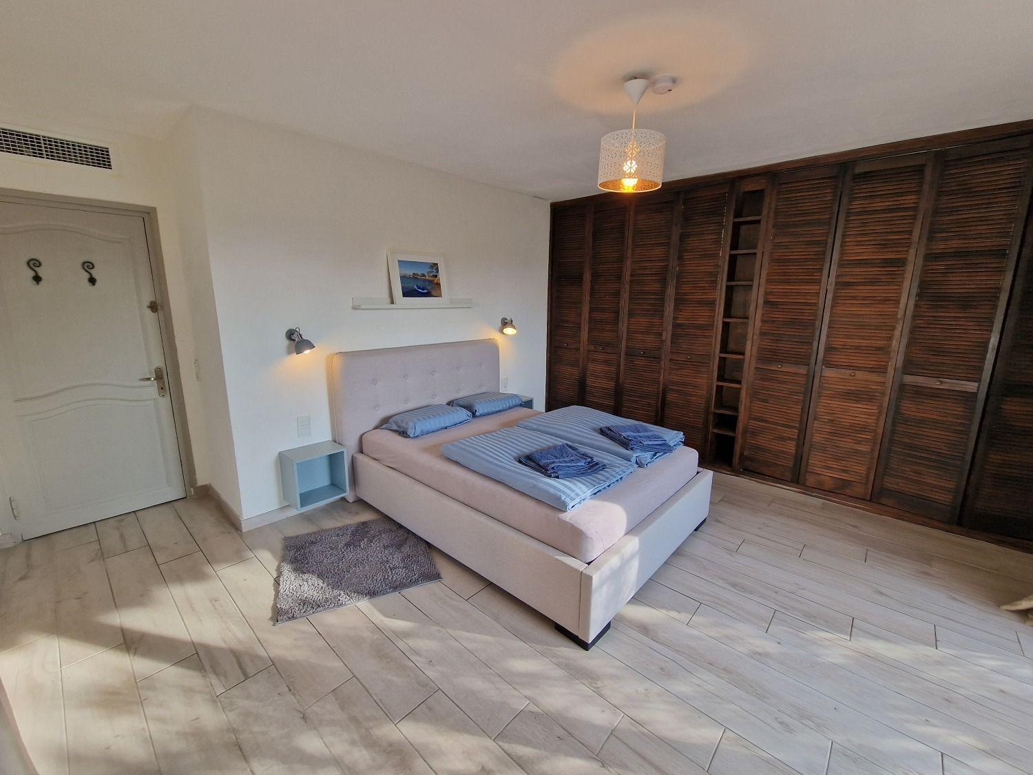 Room Antibes showing the double bed, large wooden wardrobe, and workspace with desk and chair