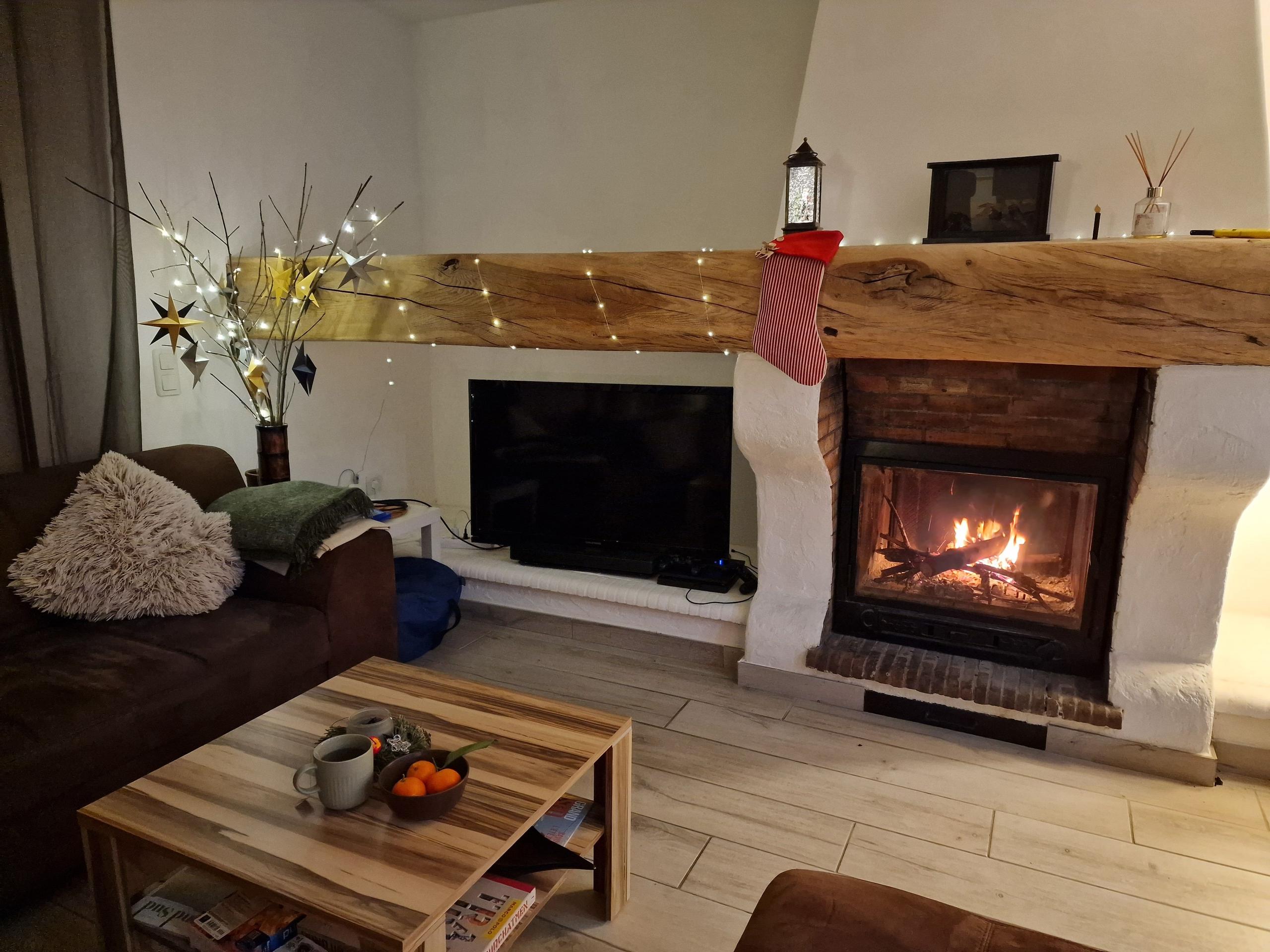 Cozy living room with a lit fireplace, TV, sofa, and Christmas decorations