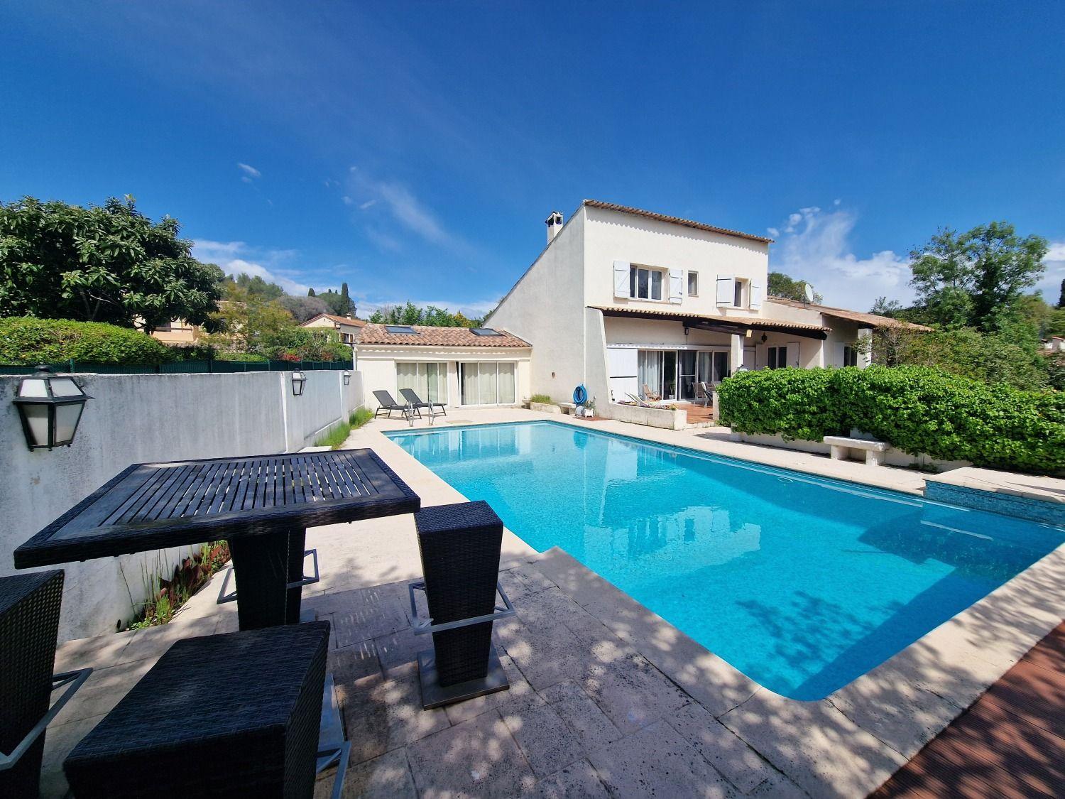 Exterior view of the villa from the pool area, showing the building facade, pool, and outdoor furniture