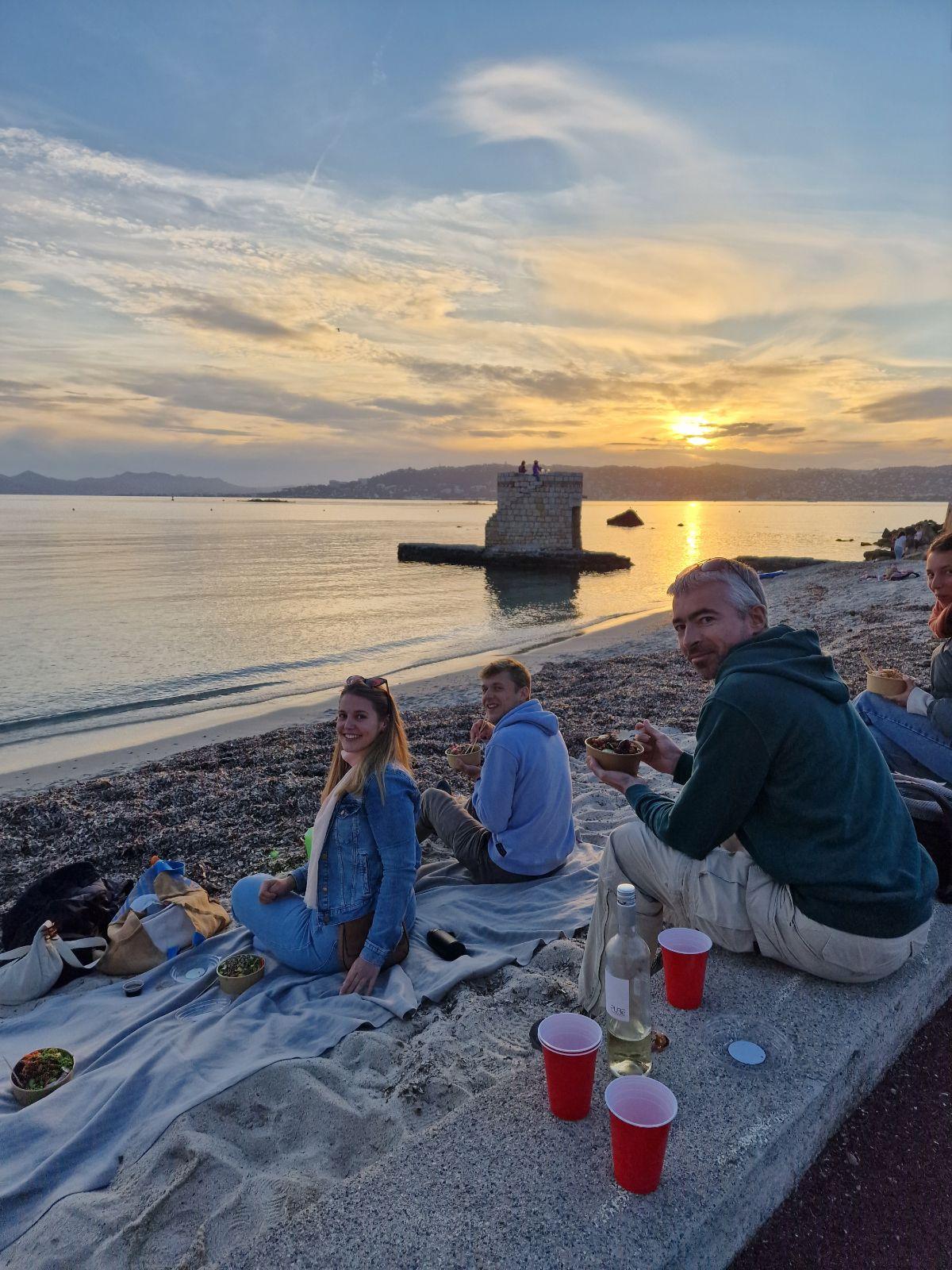 Group of residents having a picnic on the beach at sunset with a coastal tower in the background