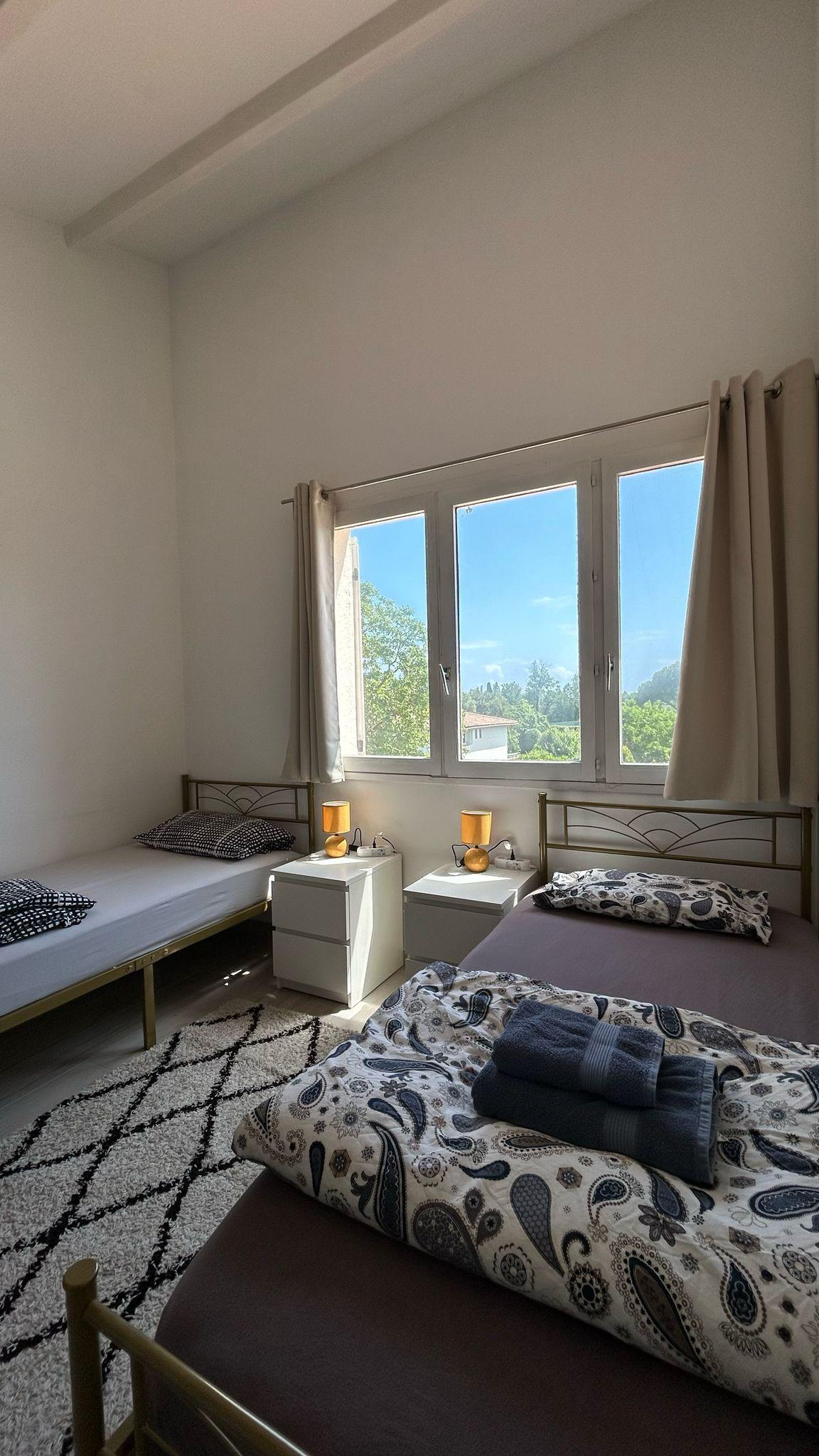 Room Nice with two single beds, nightstands, and large windows with garden views