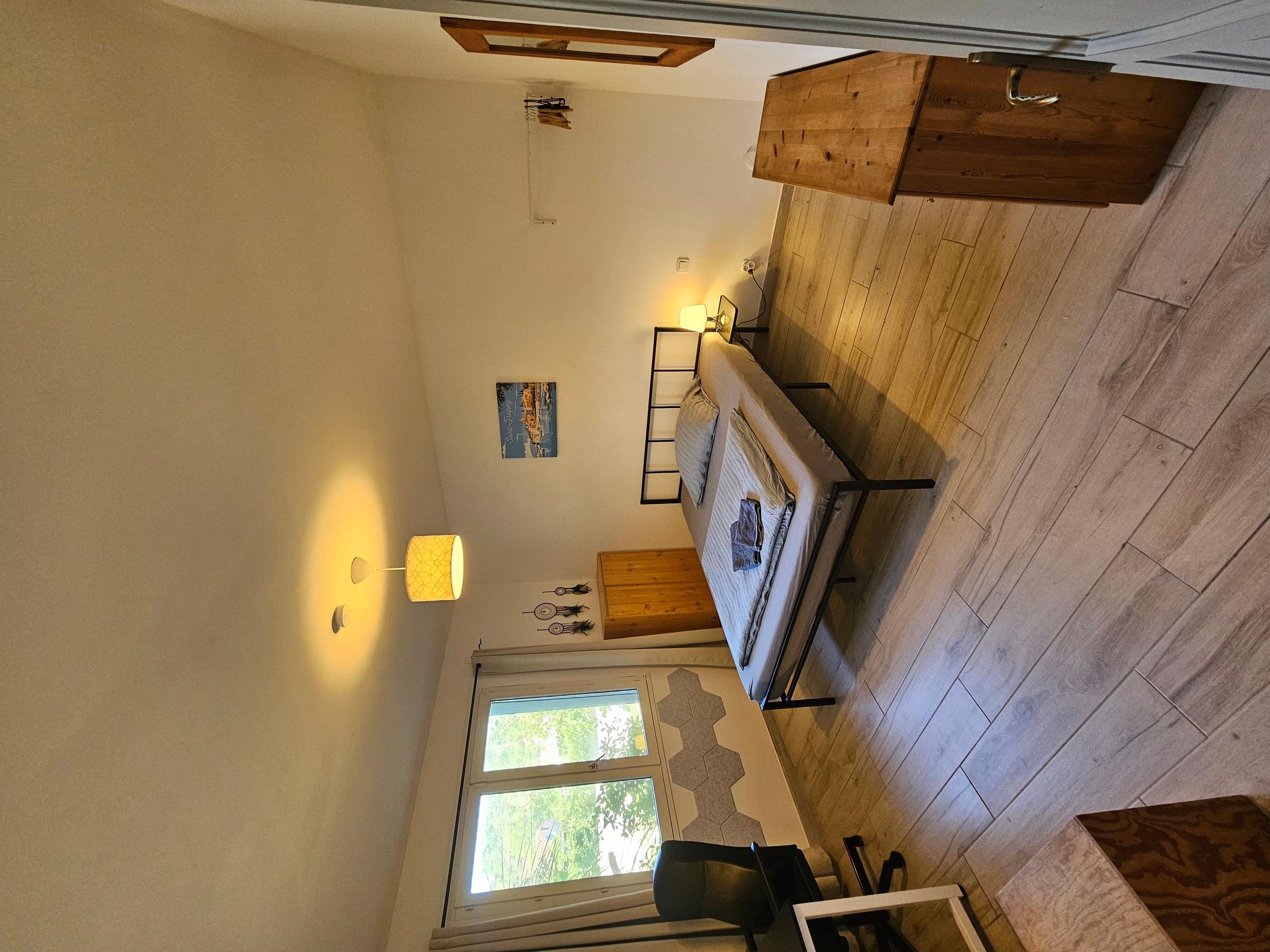 Room St. Tropez with a queen-size bed, wooden accent wall, and window