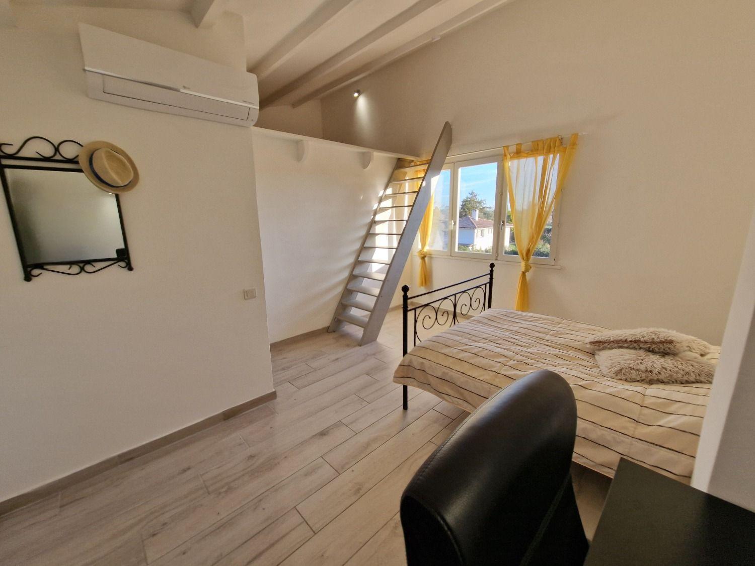Room Cannes showing the mezzanine level with staircase, bed, and window with garden views