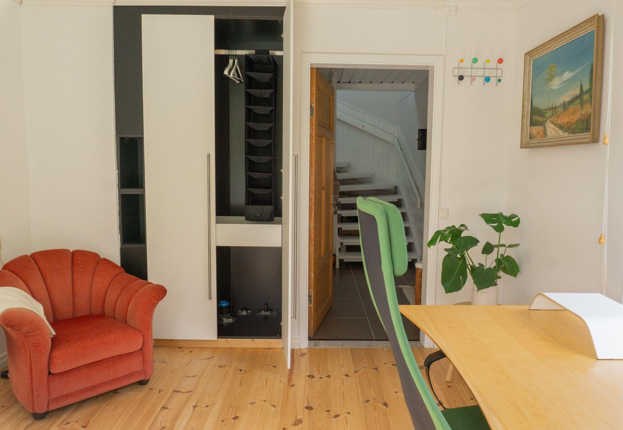 Bright shared kitchen with white cabinets, island with bar stools, mint-green SMEG fridge and garden view