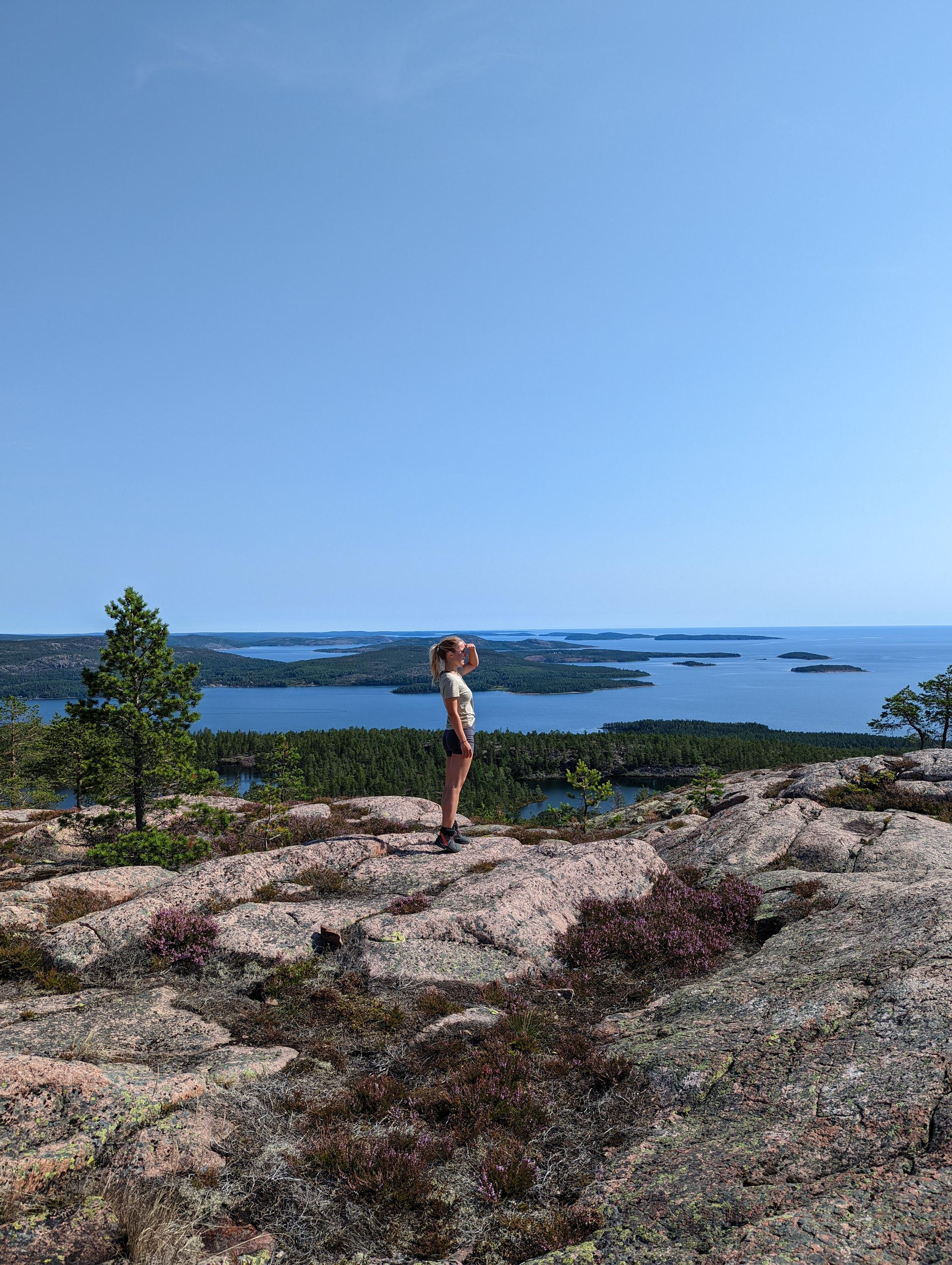 Person standing on rocky mountain top at Skuleberget with panoramic view over the Baltic Sea and islands